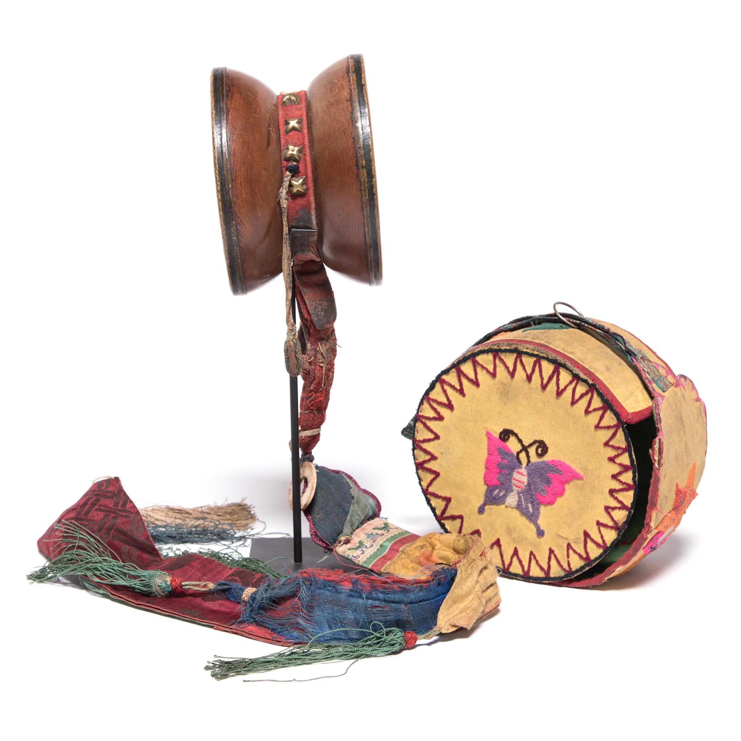 Vibrantly colored and intricately decorated, this small two-headed drum is a 19th-century Tibetan damaru, a hand-held instrument used in tantric practices within Tibetan Buddhism. Carved into an hourglass shape, this wooden drum is modeled after the