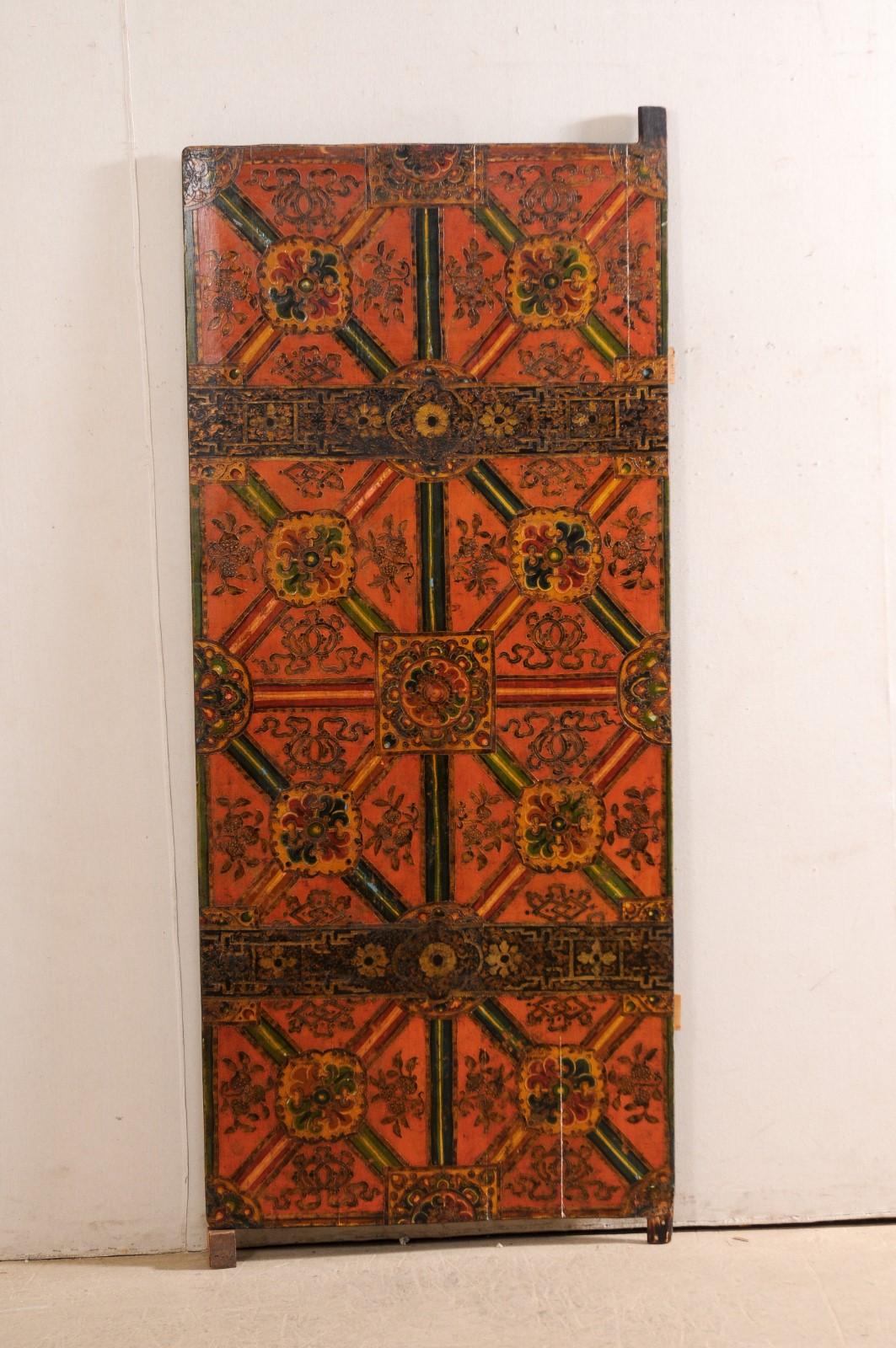 A Tibetan single artfully hand-painted wood door. This delightful vintage door from Tibet features an eight panel front design, which has been created in an artistic hand-painted motif of geometric and floral patterns. The palette is a festive