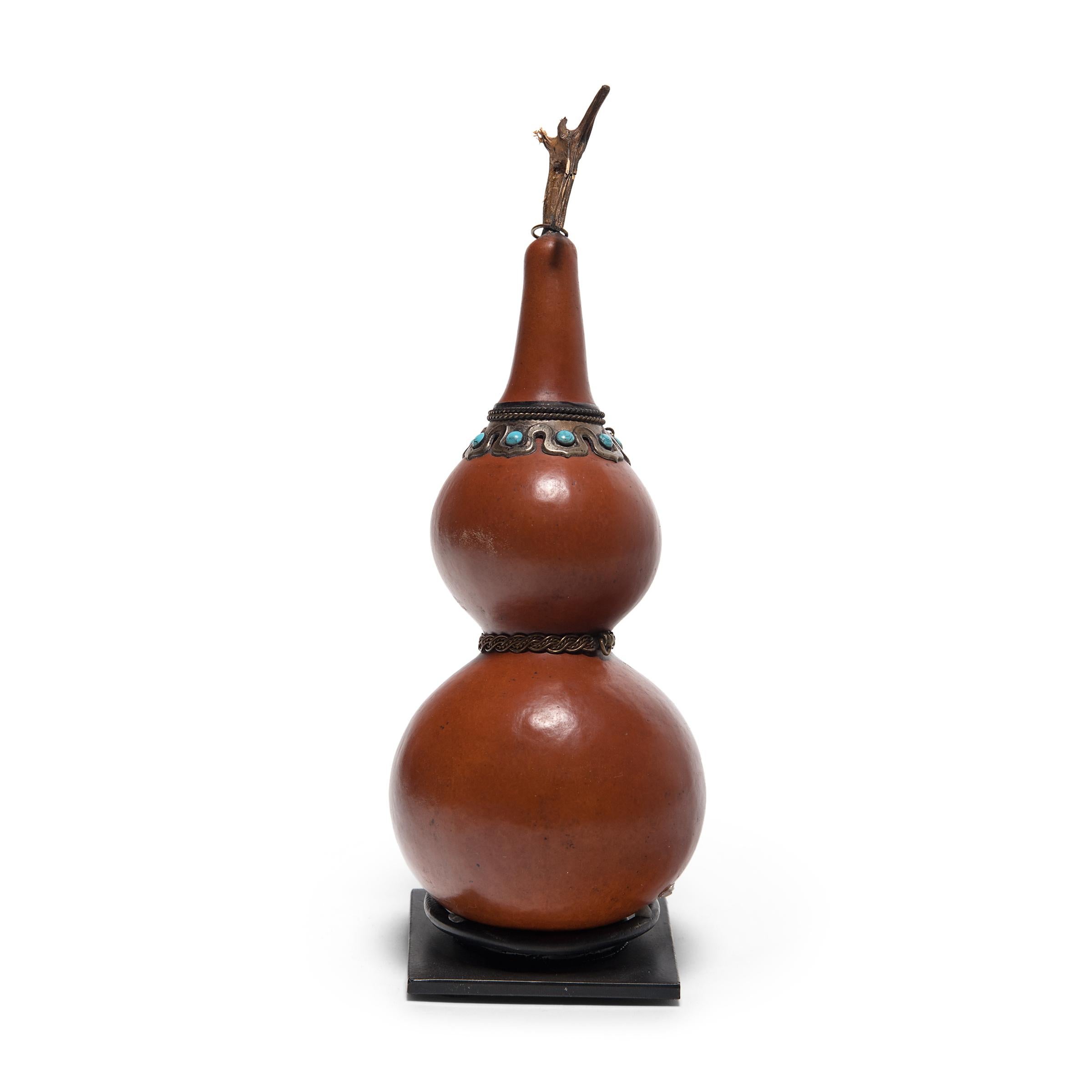 Due to their many seeds, gourds are appreciated in China and Tibet as auspicious symbols of fertility. When dried, gourds became durable natural vessels used as ladles, flasks, or even as musical instruments. This Tibetan flask is made of such a