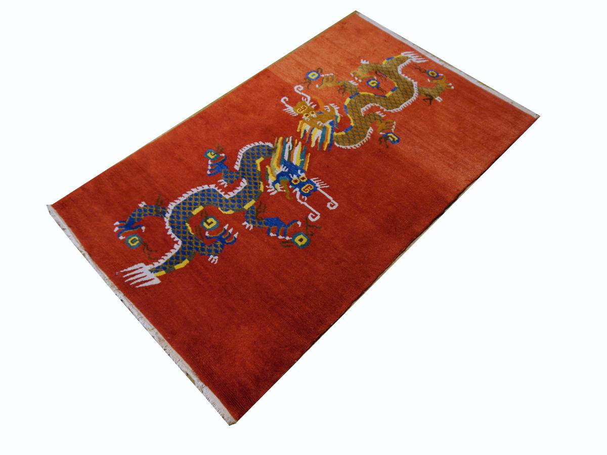 A double Dragon Tibetan rug in red field.
This traditional dragon rug design is typically found on antique rugs called Khaden. It describes a small sized rug of about 3 x 6 ft that was used in Tibet to decorate columns or seat pad. Often these