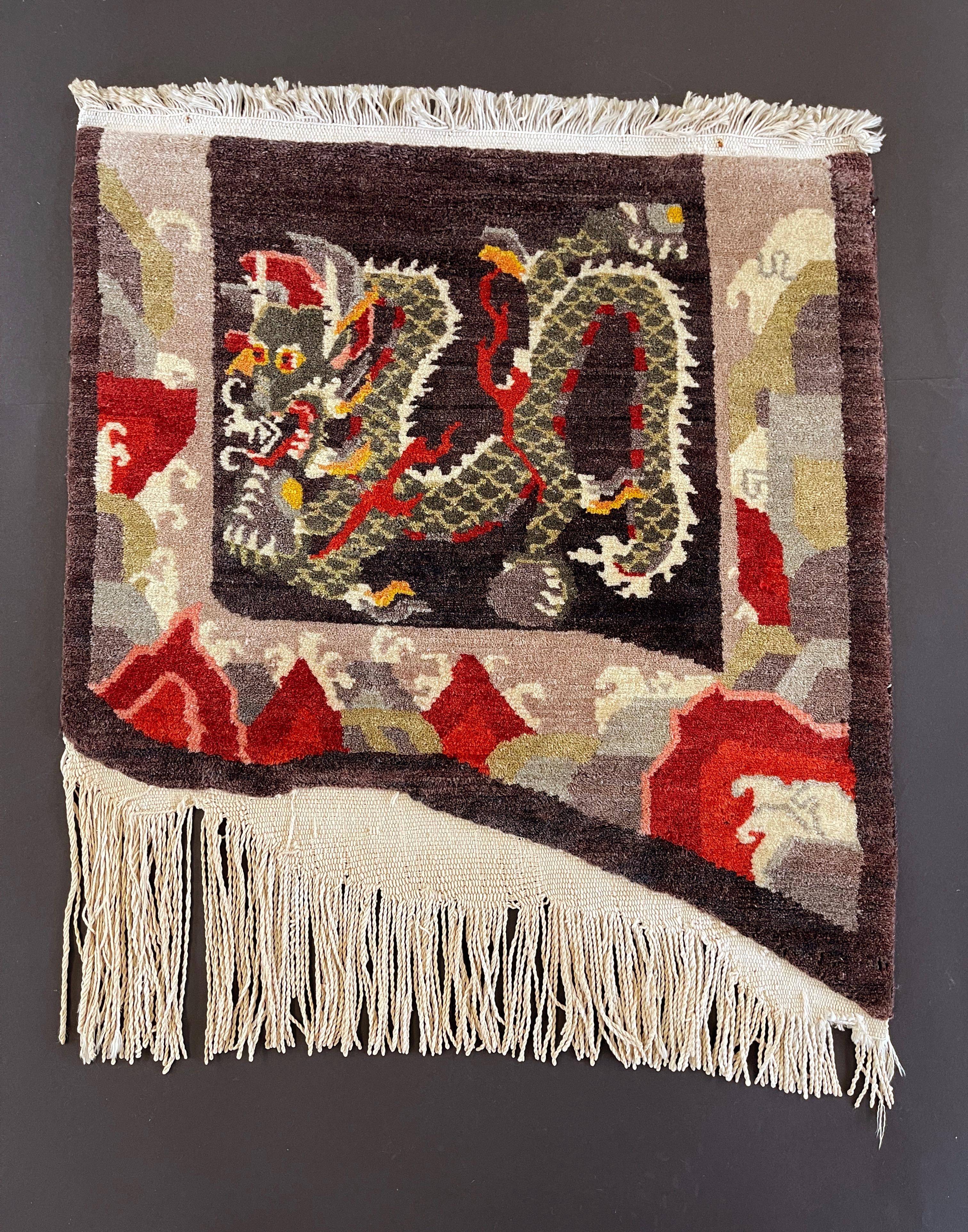 Tibetan hand knotted wool rug or tapestry, this shape reminds of a saddle bag cover.
Very decorative pure wool thick pile with asymmetrical cotton fringes.
Rare item, likely custom made, displaying a typical Tibetan symbol: the dragon with