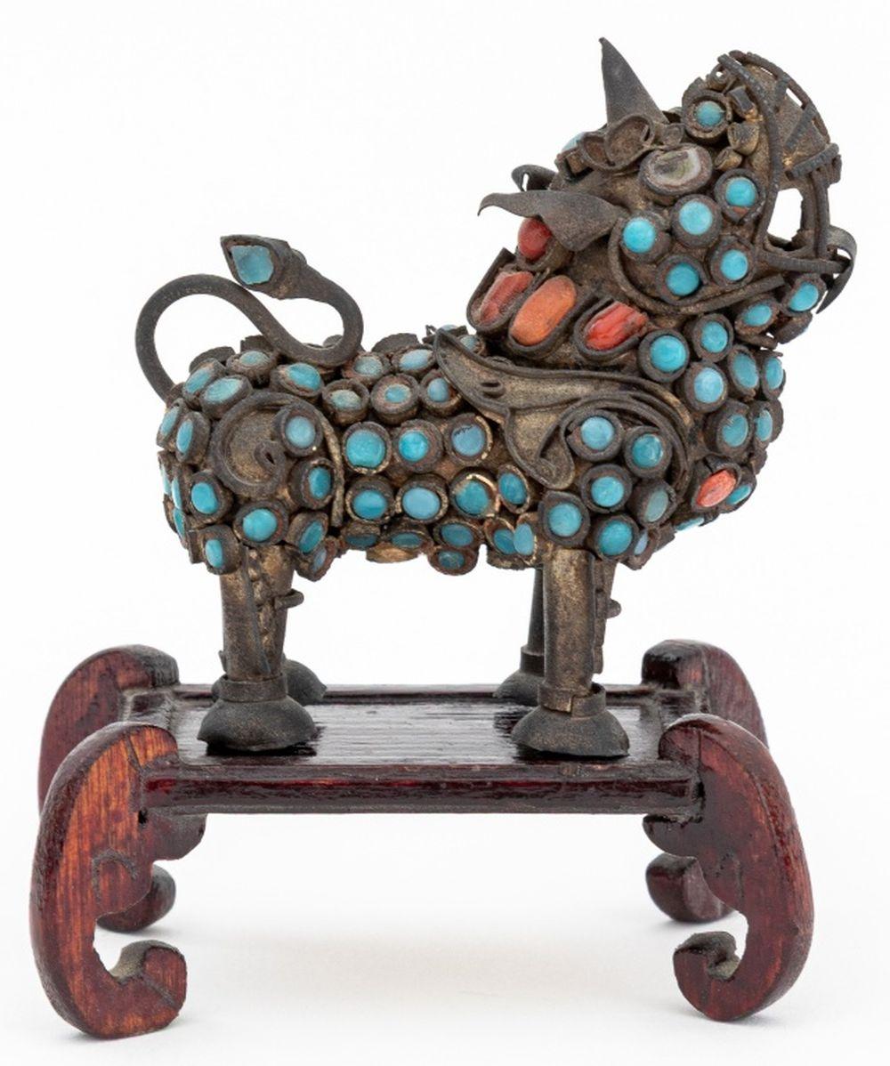 Groupe de trois objets tibétains montés en faux corail et fausse turquoise, comprenant : un moulin à prières bouddhiste avec support, une boîte couverte, et une petite sculpture de rhinocéros sur support en bois. Moulin à prières sur pied : 5,5