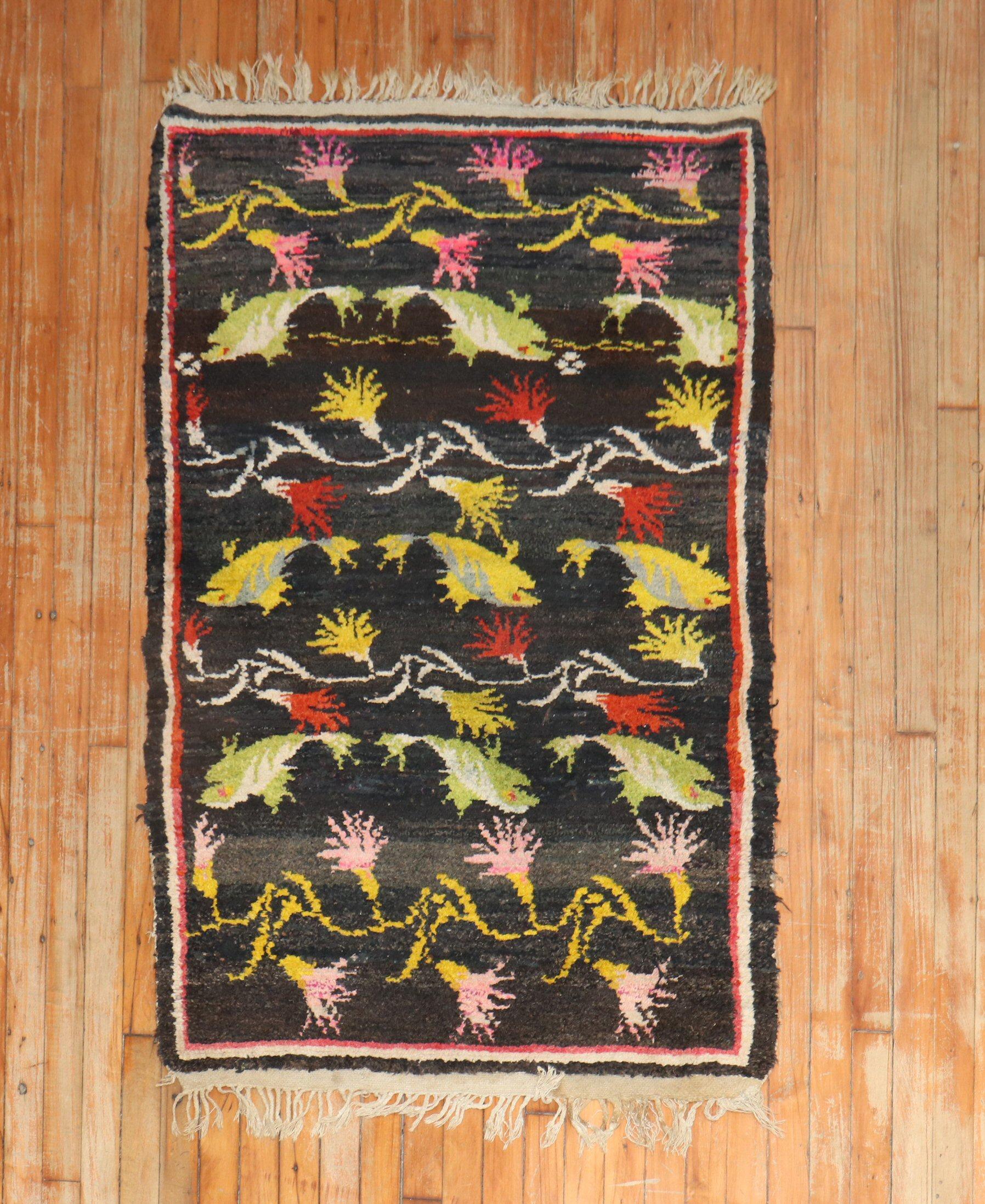 A 2ndquarter of the 20th-century highly decorative Tibetan rug with fishes floating around a floral motif on a dark ground color. 

Size: 2'10'' x 4'9''.

