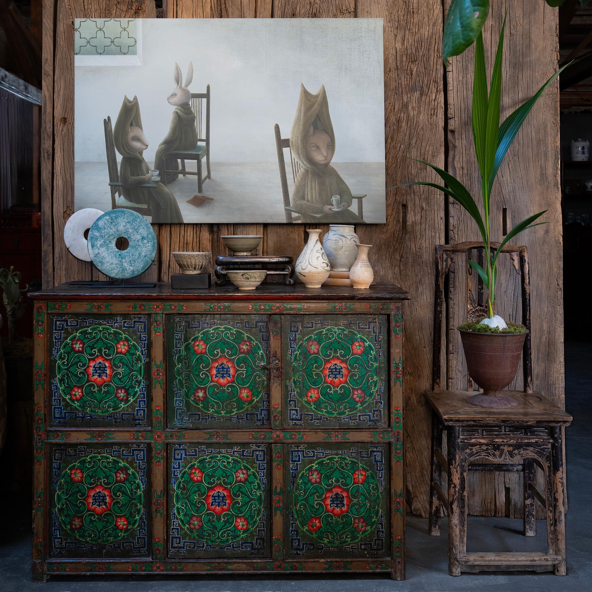 Crafted in 19th-century Tibet, this extraordinary cabinet is beautifully decorated from end to end with hand-painted floral motifs. Brushed in a cool palette of green, red, blue and gold, the painted facade is a celebration of traditional artistry