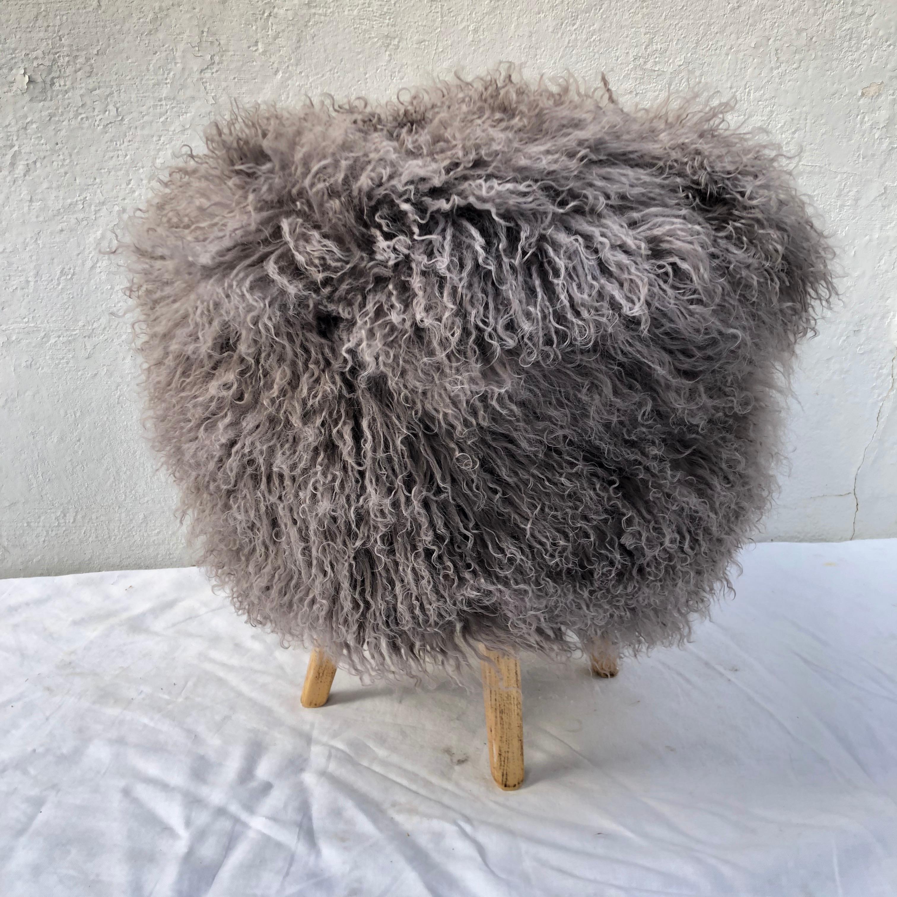 Newly upholstered stool/ ottoman in long hair warm gray Tibetan lamb with four wood legs...

It measures 19