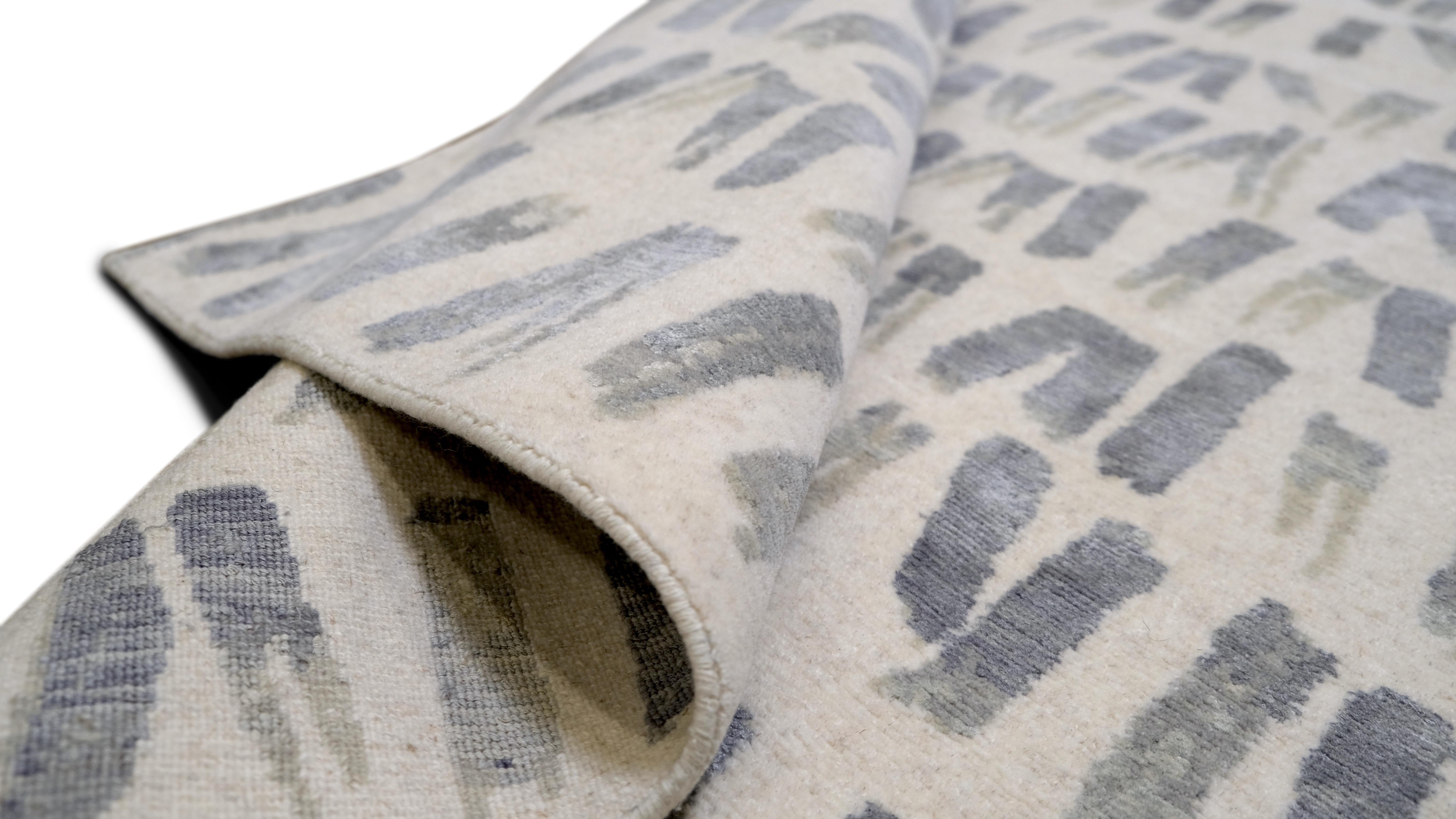 Présentant un motif géométrique abstrait moderne dans des tons de bleu gris argenté et de blanc, cette pièce est à la fois visuellement intrigante et polyvalente, ce qui en fait le complément idéal d'un intérieur moderne ou minimaliste. Son design