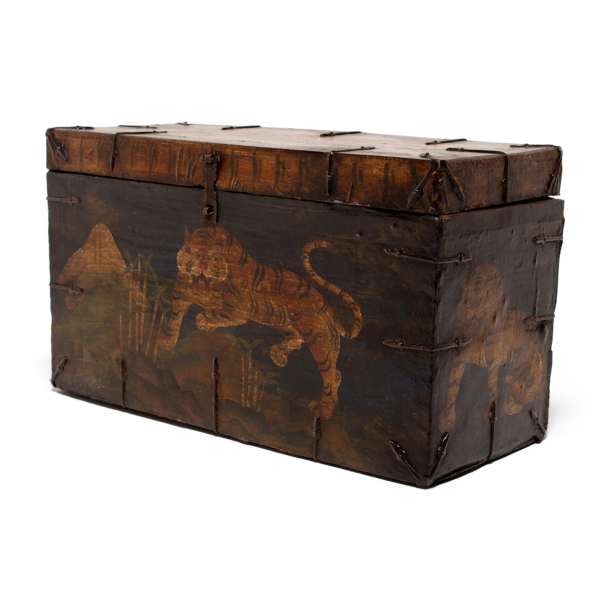 This Tibetan storage chest is richly finished with lacquered hide and iron hardware. The front is hand-painted with a fearsome tiger prowling a lush, mountainous landscape. Considered the king of all terrestrial creatures, the tiger is depicted