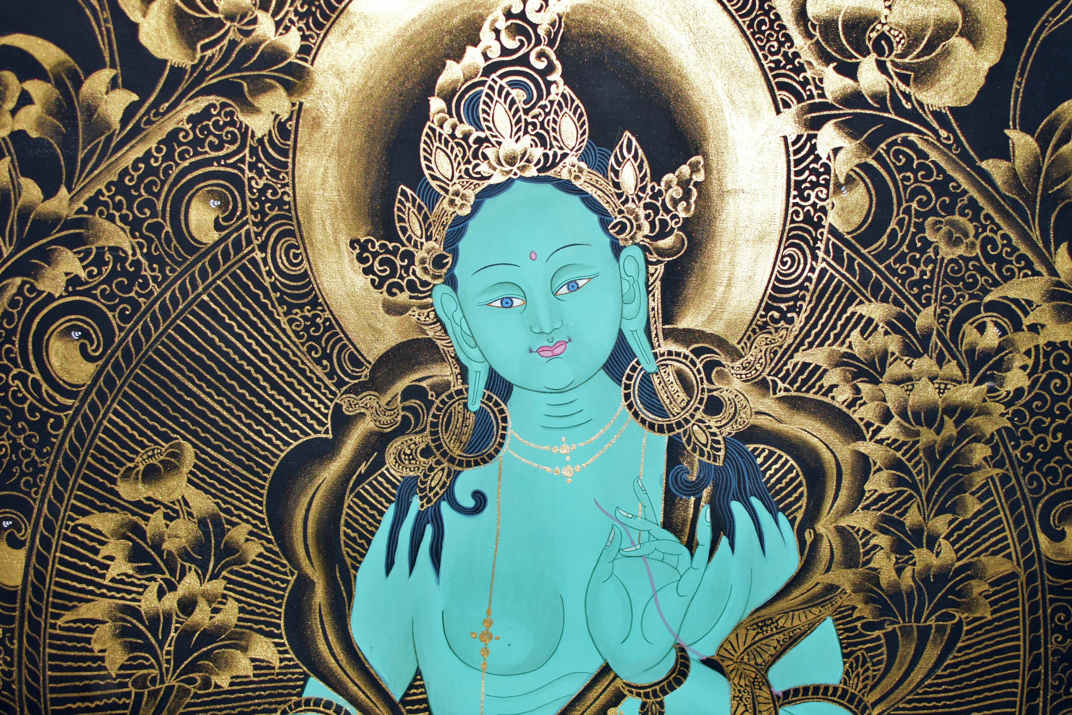 An extraordinary hand painted Tibetan Thangka featuring the greatest compassion Goddess Green Tara. Her round face with large kind eyes, above closed lips, all flanked by long pendulous earlobes. Wearing an elaborate crown, lariats, earrings,