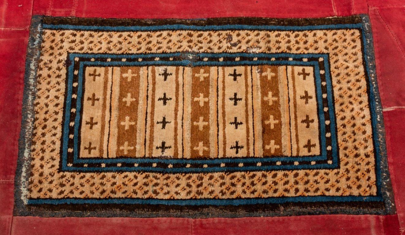Tibetan Prayer Rug. Encased in a large hand-sewn red cotton textile border, underside backed with cotton. 

Dealer: S138XX