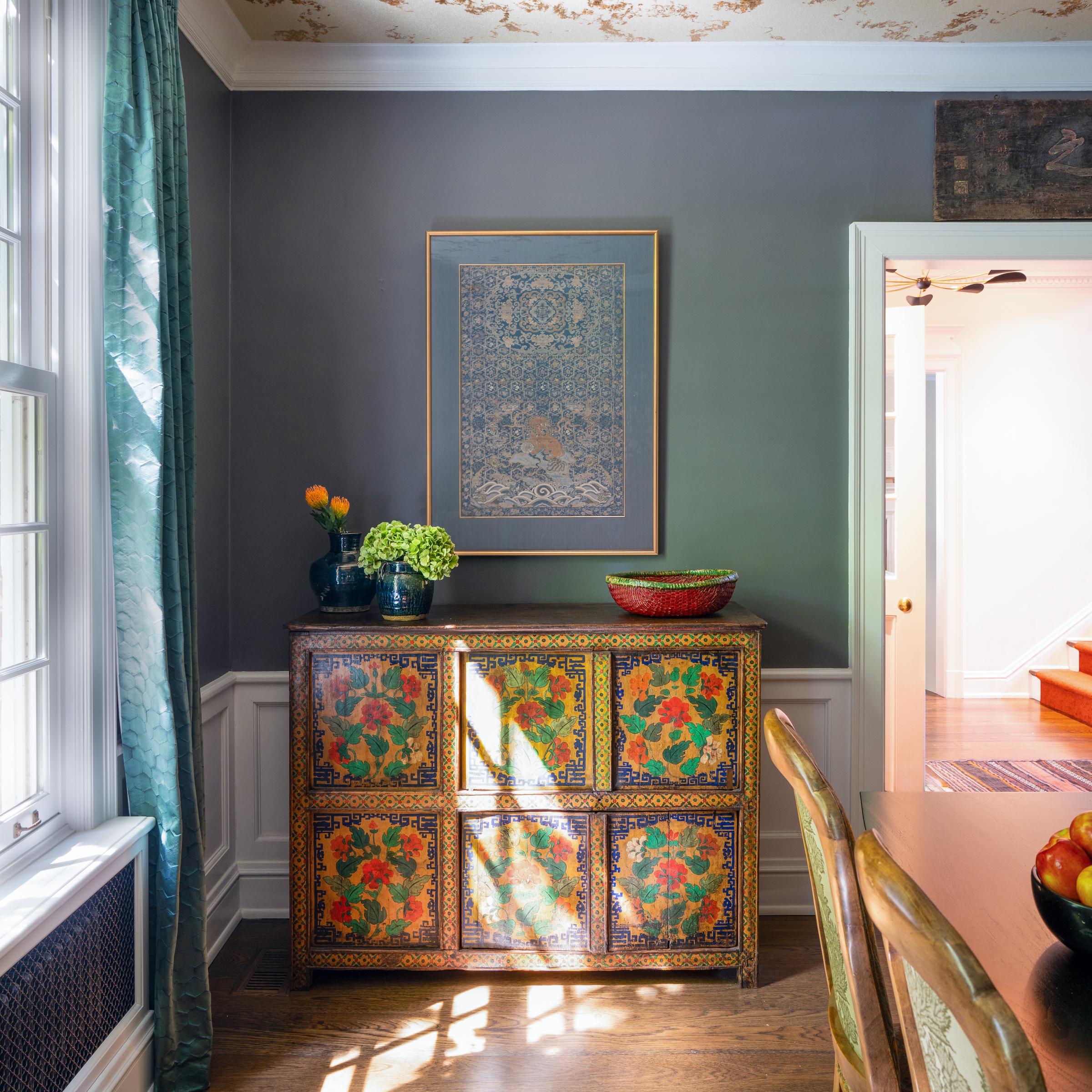 Dieser Schrank aus dem frühen 20. Jahrhundert ist im sino-tibetischen Stil mit üppigen Blumen und botanischem Schnörkelwerk bemalt. Das von Hand gepinselte Design in einer fröhlichen Farbpalette aus Goldgelb, Rot-Orange, Grün und Marineblau
