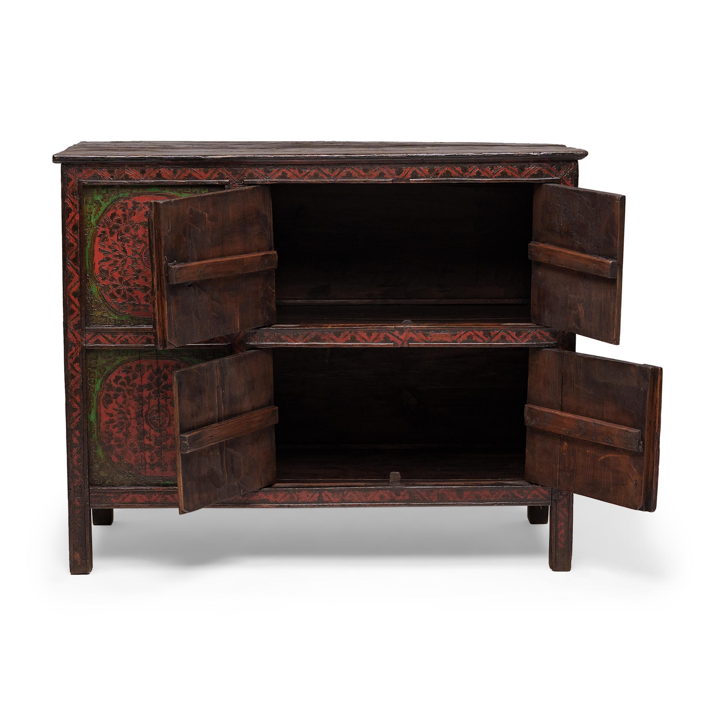 Crafted in 19th-century Tibet, this captivating storage cabinet is beautifully decorated from end to end with vibrant red and green pigments. Densely patterned with incredible detail, the hand-painted facade is a celebration of traditional artistry