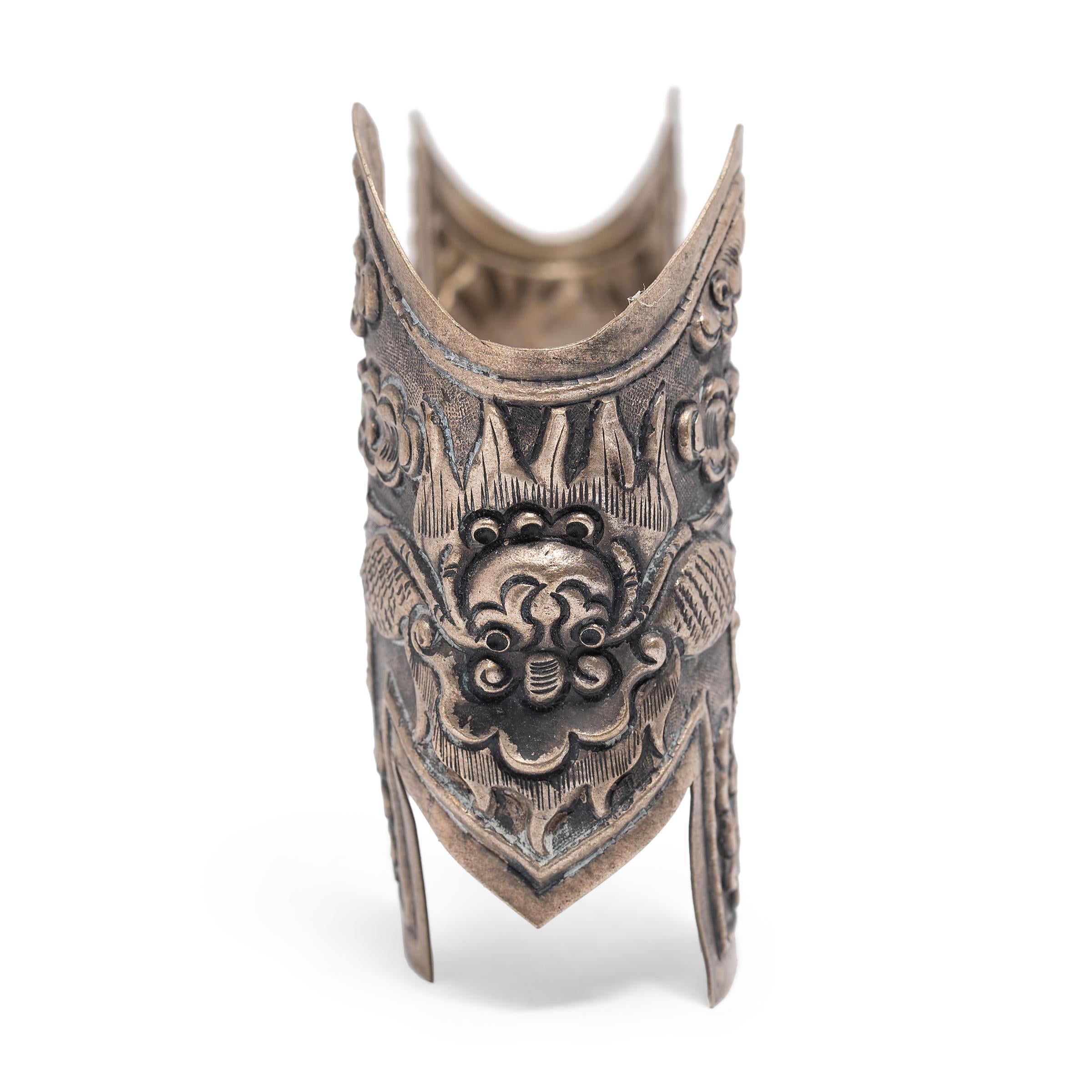 This unusual piece of silver hardware is wonderfully patterned with intricate Tibetan repoussé decoration. Comprised of two thin silver plates linked by a straight rod, the metal fitting is decorated on each side with a fearsome dragon, his feet in
