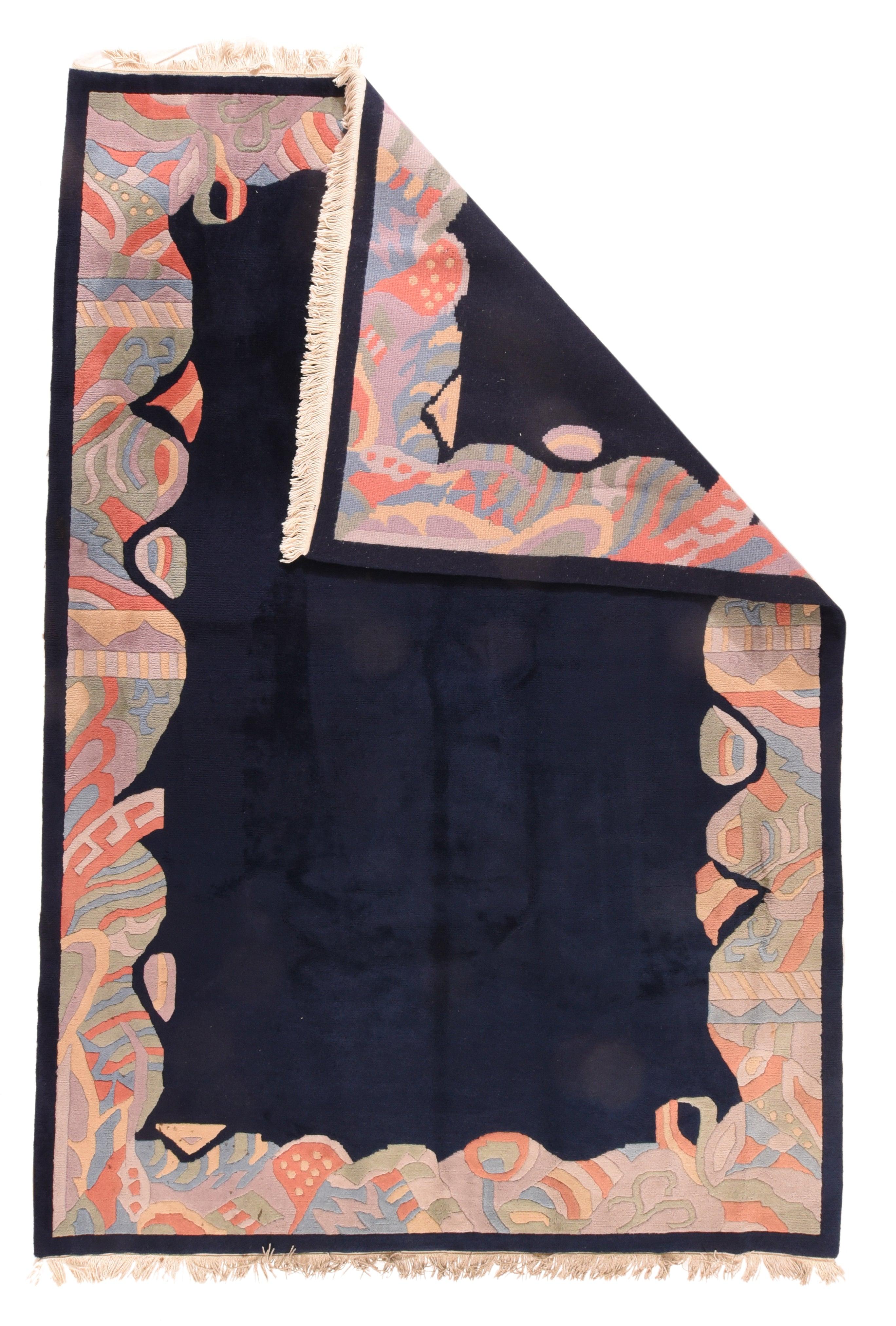 Tibetan Rug 6'5'' x 9'5''. The deep navy open field is erratically edged with a surging and fracturing border highlighted with bits of ribbon, fretwork fragments, and various dotted and banded softly polychrome motives. All contours beveled neatly.