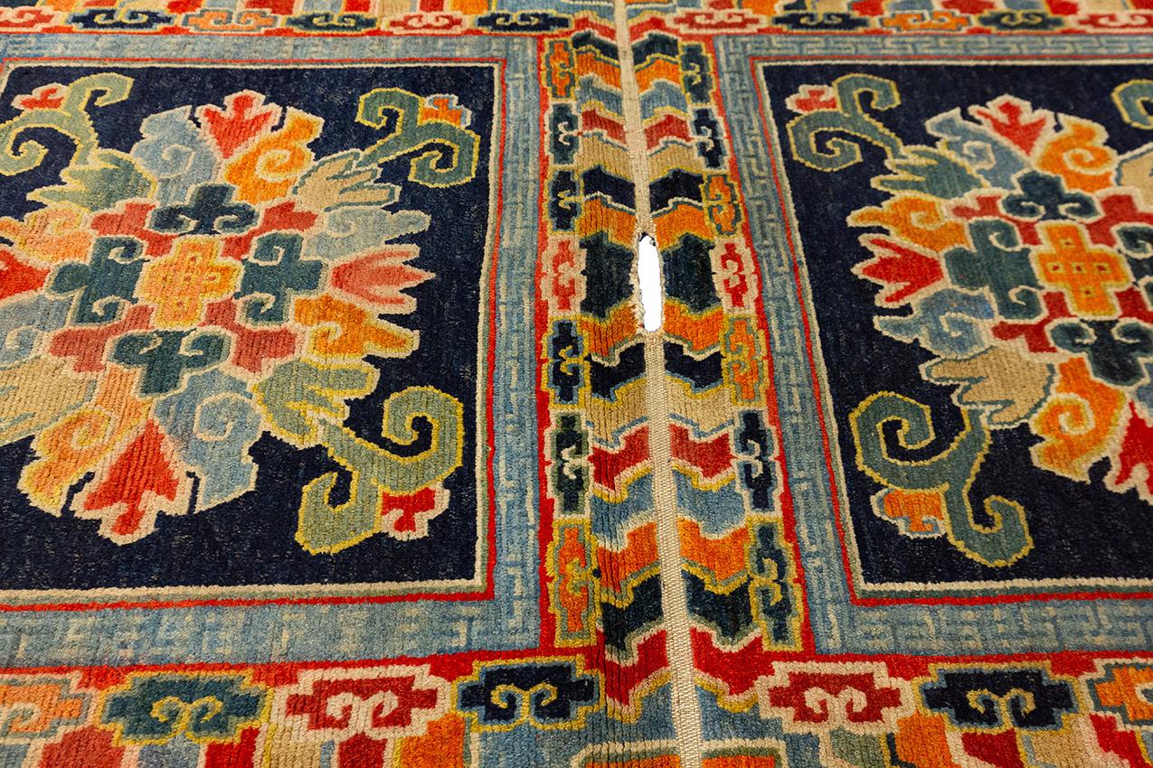 Antiker tibetischer Doppelteppich, 142cm x 86cm Das anthrazitfarbene Feld enthält jeweils ein großes mehrfarbiges, offenes Blumenmedaillon. Innen hellblauer Streifen mit Schlüsselmuster. In polychromem Meereswellen- und Wolkenband offener Rand.