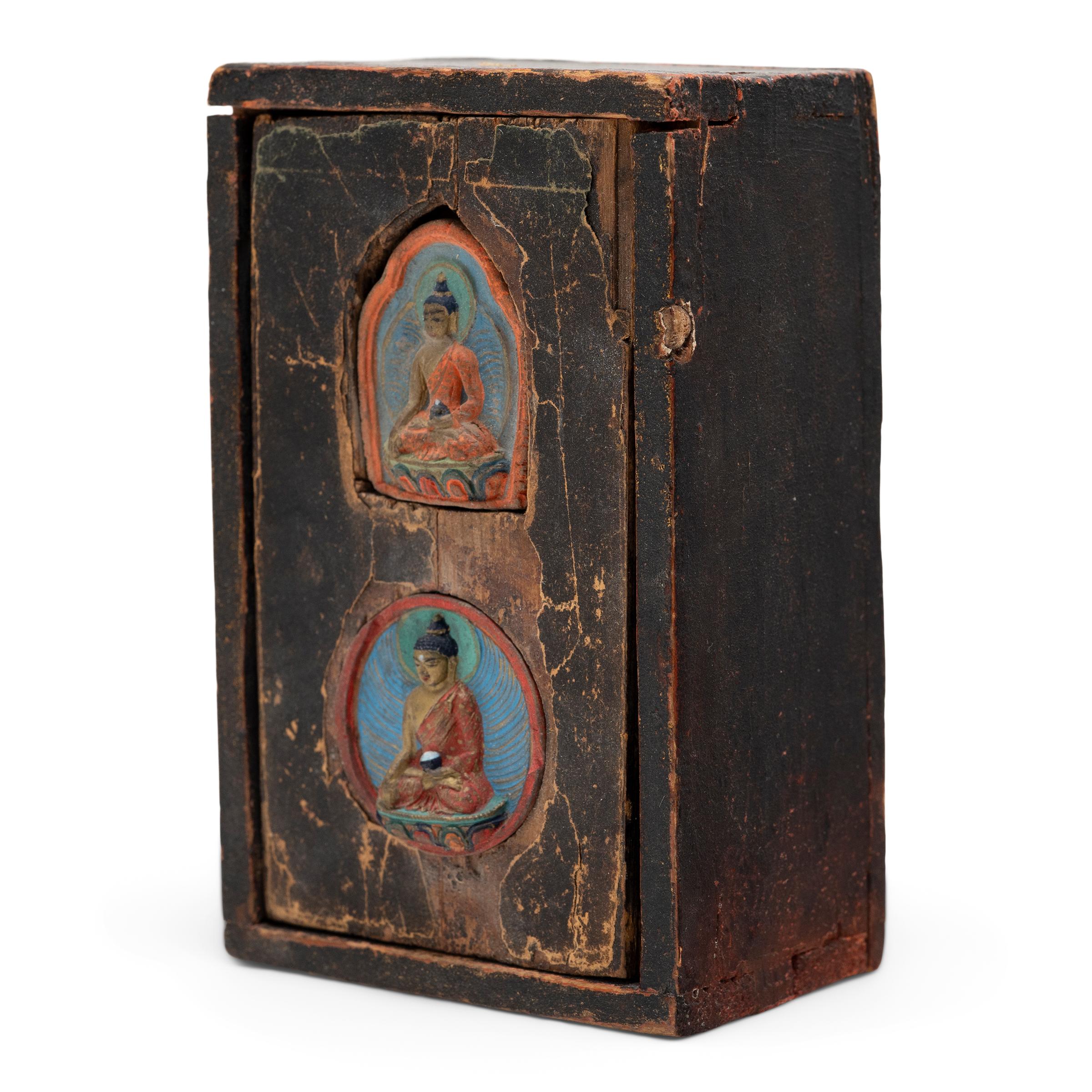 Adorned with Buddhist iconography and enveloped in a rich patina, this small wooden box is a 19th century portable Tibetan shrine and likely once contained a Buddhist statue or prayer scroll. The lid of the shrine is inset with two small, molded