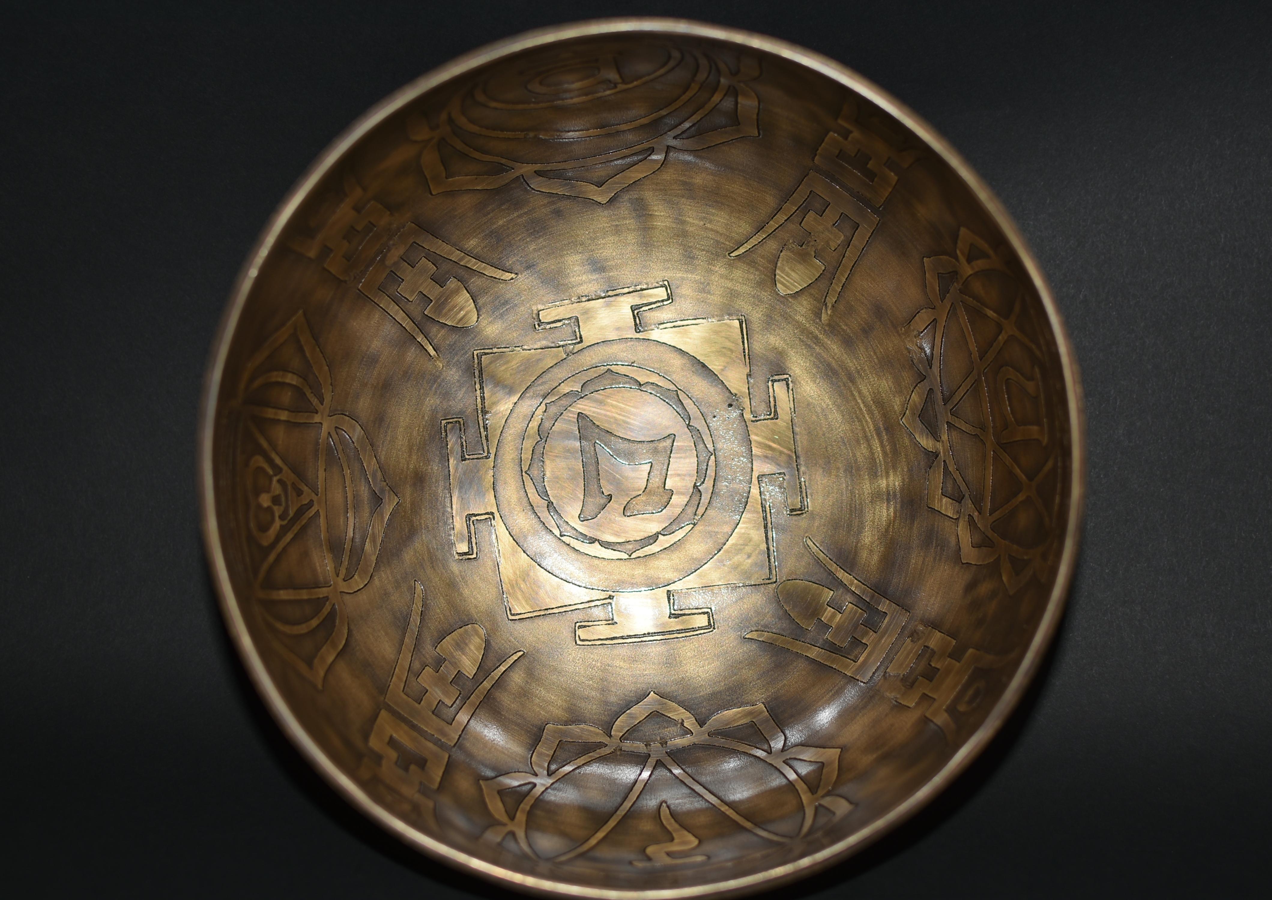 A beautiful, fully engraved and inlaid singing bowl made by the spiritual craftsmen of Nepal. The interior depicts a center square surrounded by four longevity characters and open lotus blooms. The exterior features rings of holy fires and royal