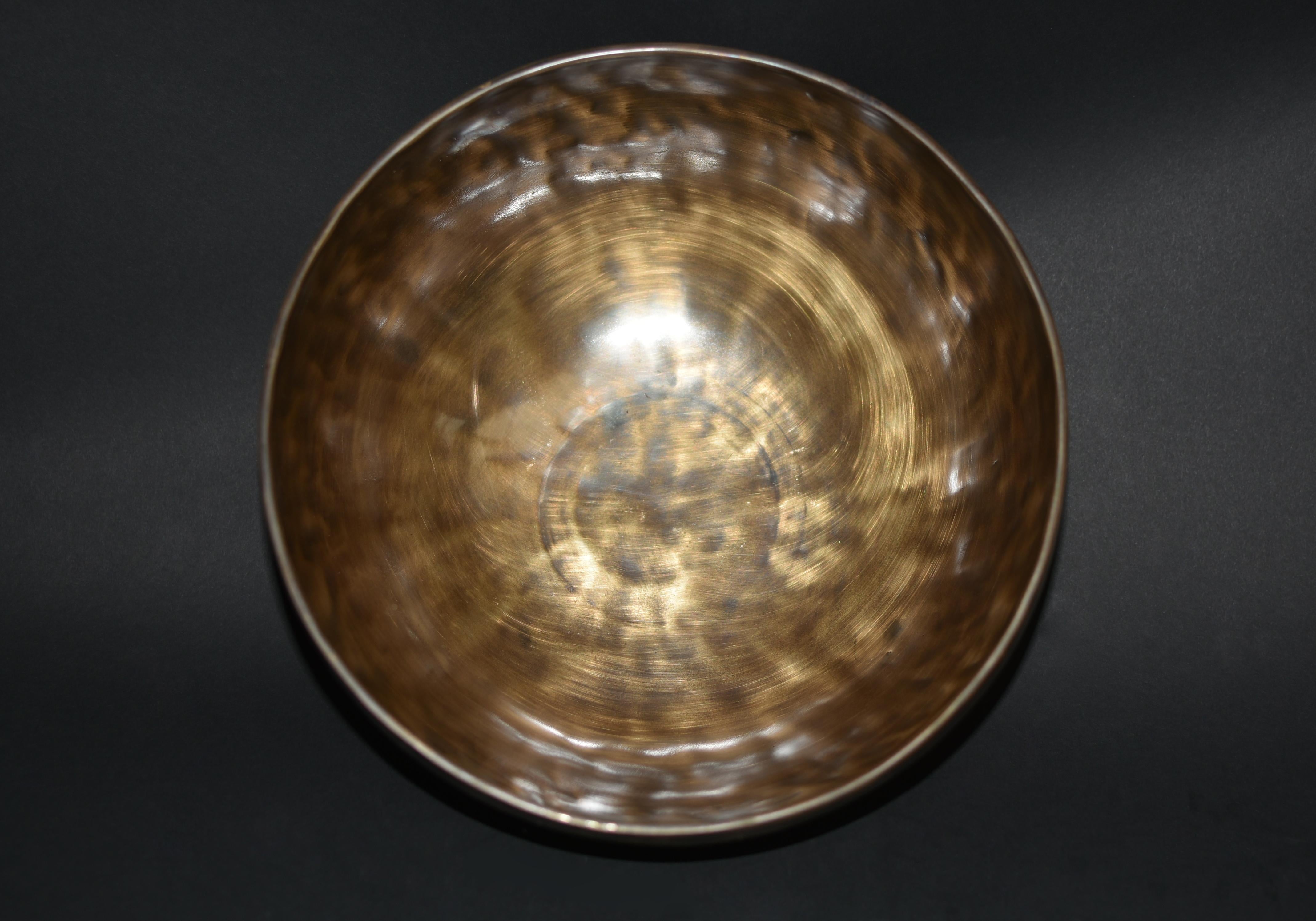 An elegant hand crafted singing bowl made by the spiritual craftsmen of Nepal. The bowl is void of decorations except a simple motif of longevity and 2 lines of Sanskrit mottos. Hand hammered, the 3.5 lb bowl has fluid vibration and beautiful tone