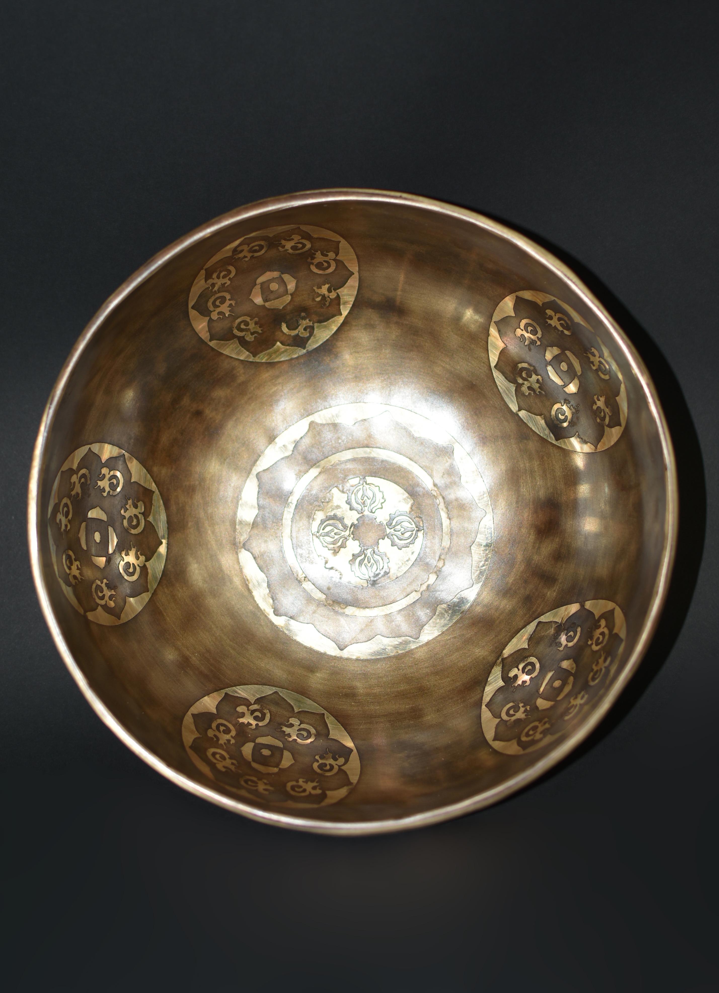 An extraordinary, one of a kind, D tone, 4.05 lb, fully engraved, inlaid, finely crafted singing bowl made by the spiritual craftsmen of Nepal. The interior depicts a center medallion surrounded by five circles, all with a background of open lotus