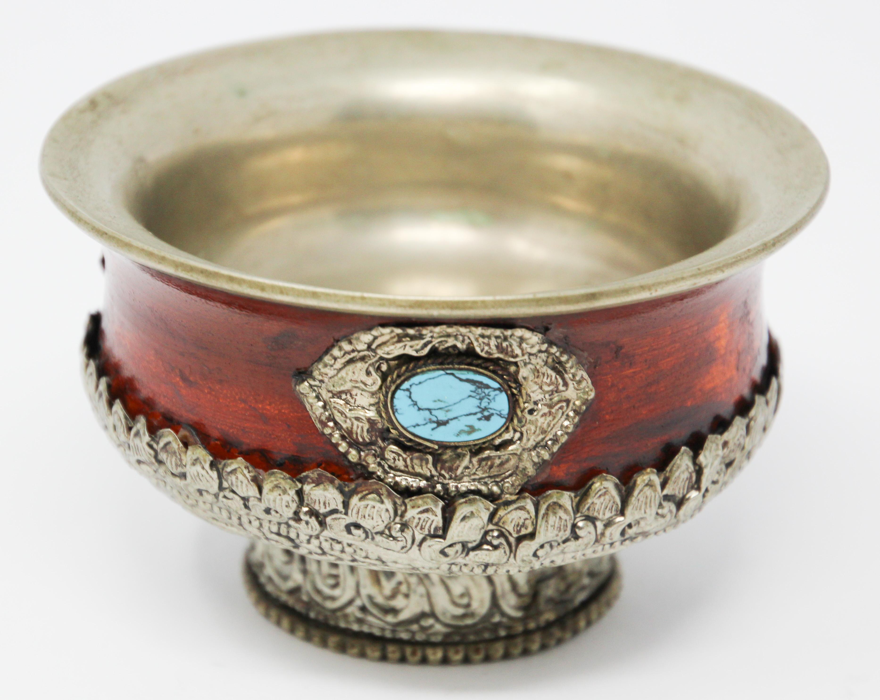 Handmade Asian highly decorative offering ceremonial bowl in Tibetan style.
Red lacquerware, trimmed with embossed metal and turquoise-colored stones inlaid. 
The interior is made of stainless steel to hold the offering water or tea, the circular