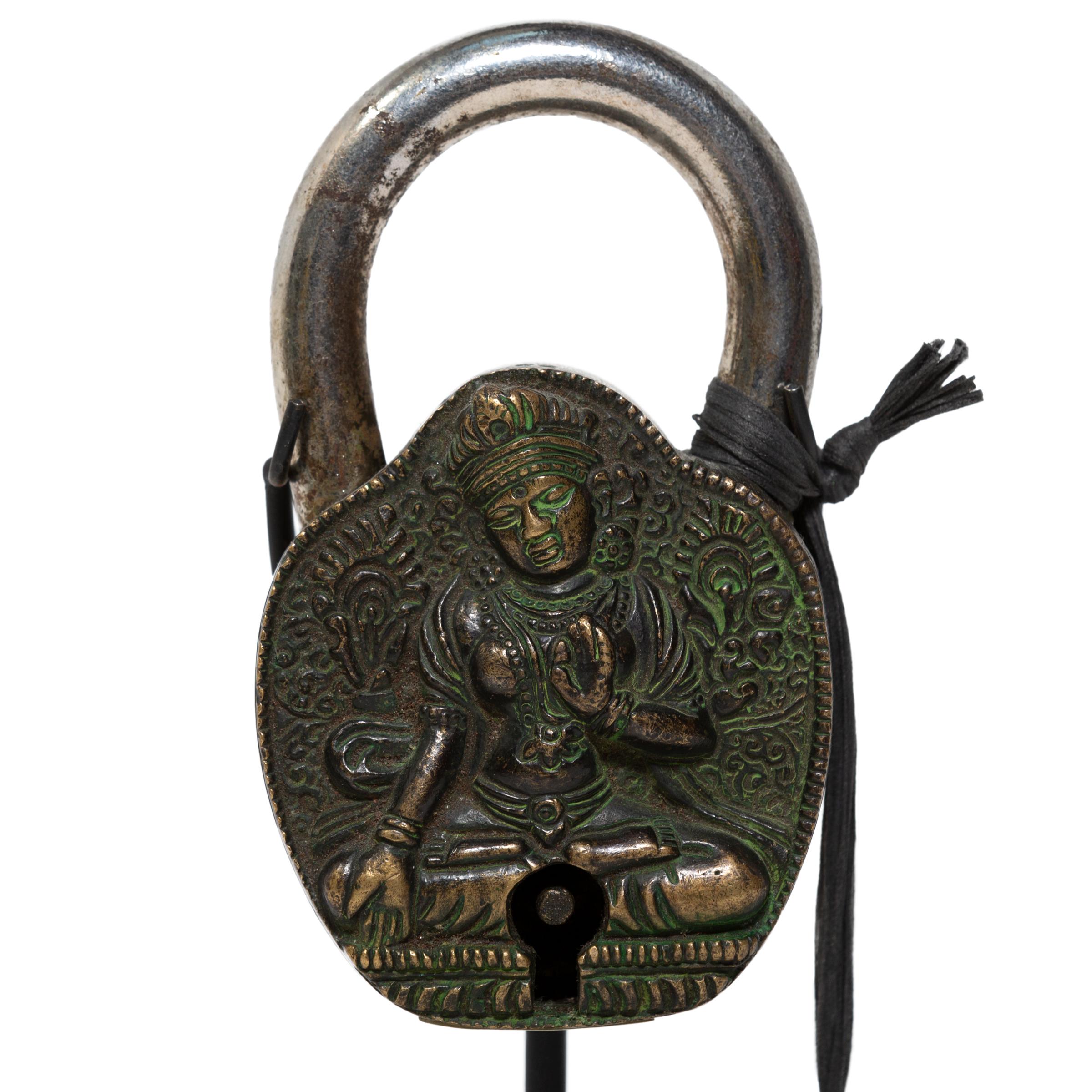 Cast in high-relief with intricate detail, this fully functional padlock is a fantastic example of 19th-century Tibetan metalwork. The lock depicts the female bodhisattva known as Jetsun Dölma, or White Tara. Seated upon a lotus throne, she holds