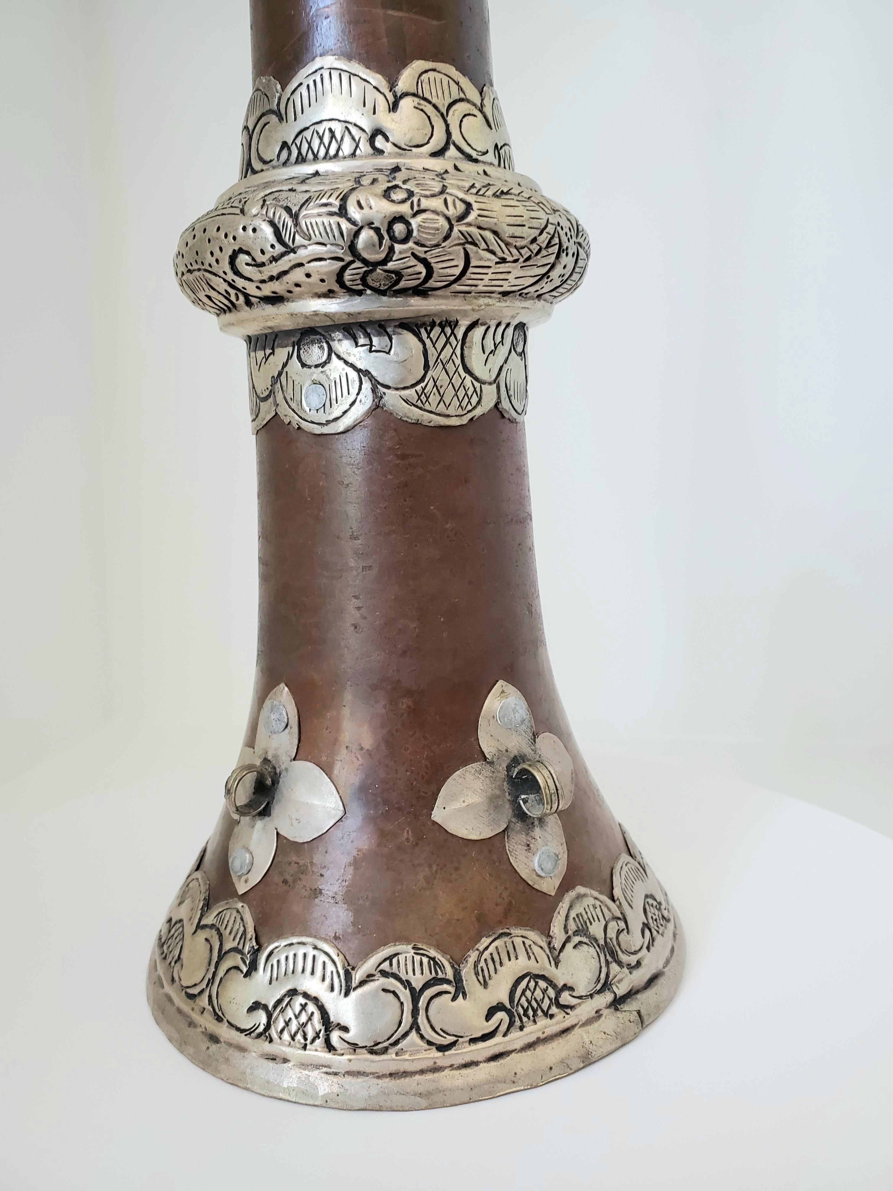 This stunning Tibetan telescopic horn or dungchen is from the late Qing Dynasty. The body is a warm brown that is smooth and adorned with chased and repoussé silvered metal details. It stands 15 inches when collapsed and 35.75 inches when extended.
