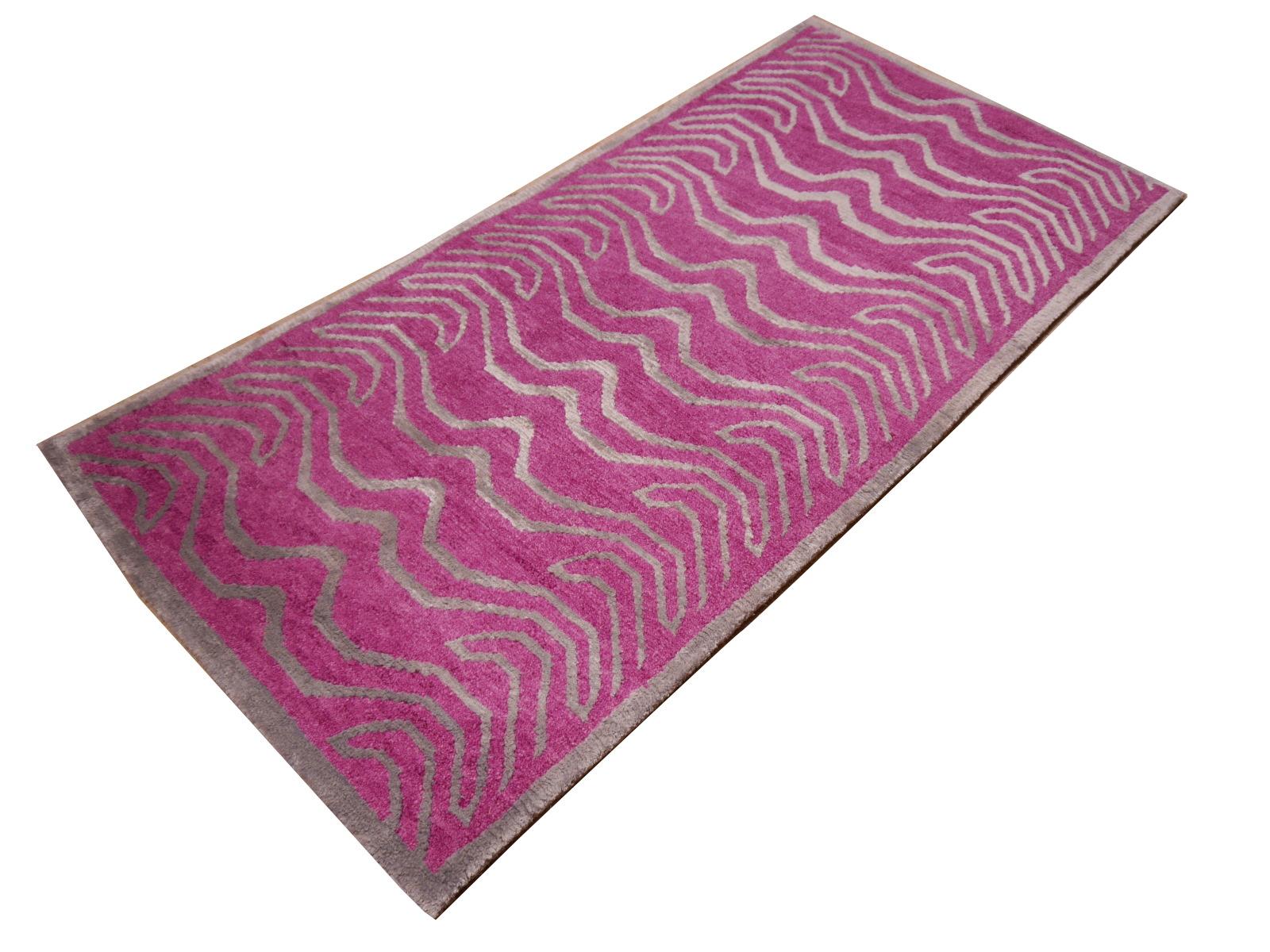 Ein rosa und silberfarbener tibetischer Tiger-Teppich, handgeknüpft in Nepal.

Dieses traditionelle Tiger-Muster findet sich typischerweise auf antiken Teppichen, die Khaden genannt werden. Er beschreibt einen kleinen Teppich von etwa 3 x 6 Fuß, der