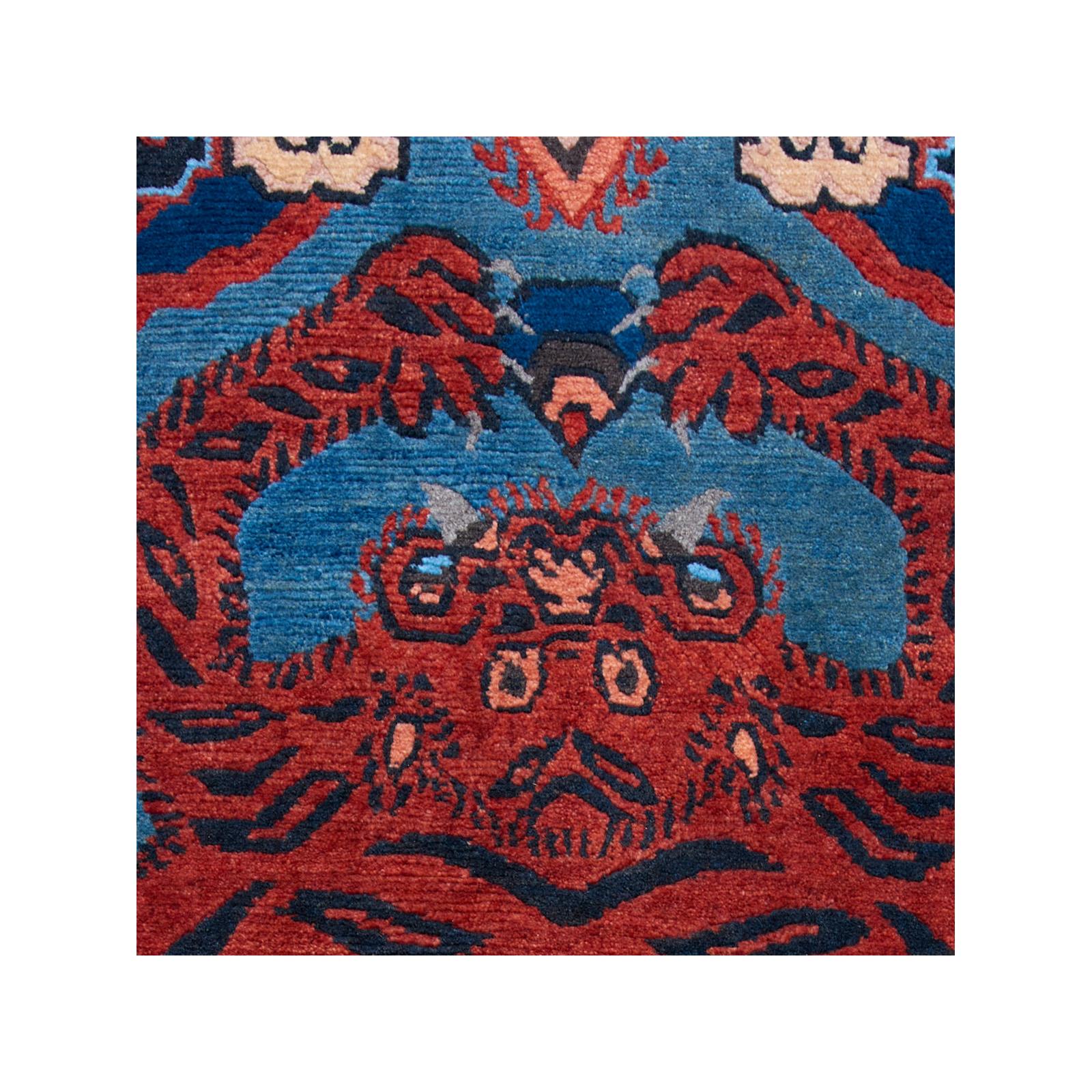 A striking Tibetan tiger skin rug, produced in the mid 20th century, displaying a flattened animal holding a jewel. Each end of the carpet has a colorful cloud border, and the sides are adorned with symbols, including a central swastika. 

Rug