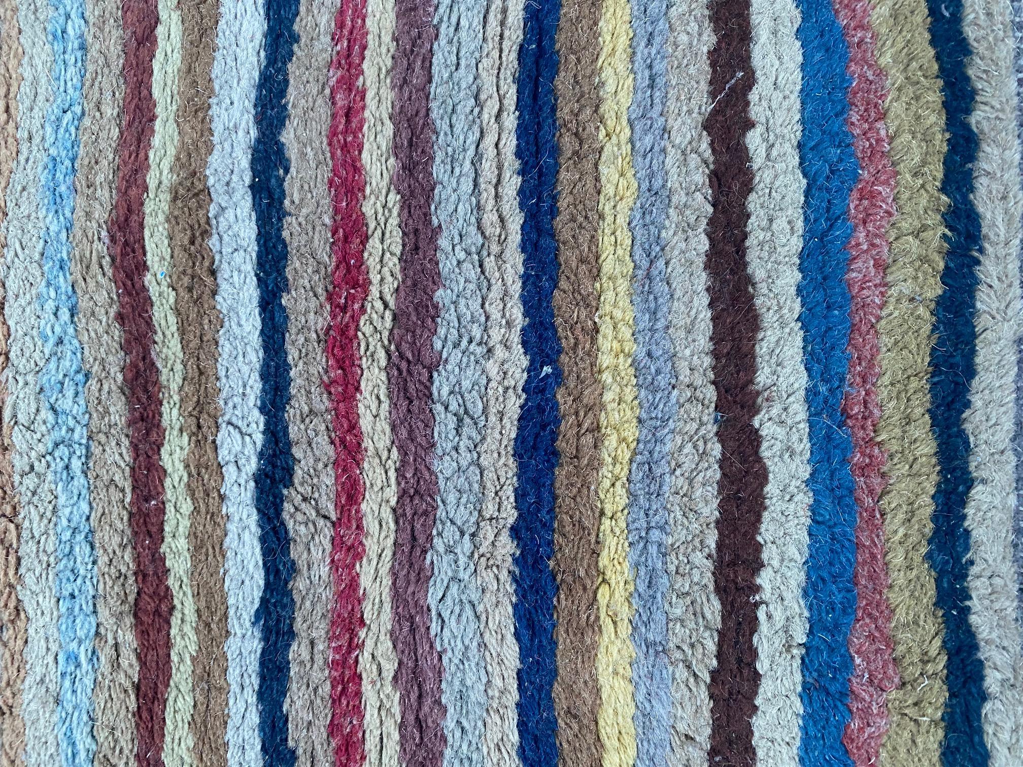 Tibetan wool striped scatter rug, circa 1950, a hand knotted wool carpet featuring a series of vibrant multi-colored stripes. Rug remains in excellent condition.

Measures: 59 in Long x 32 in Wide.