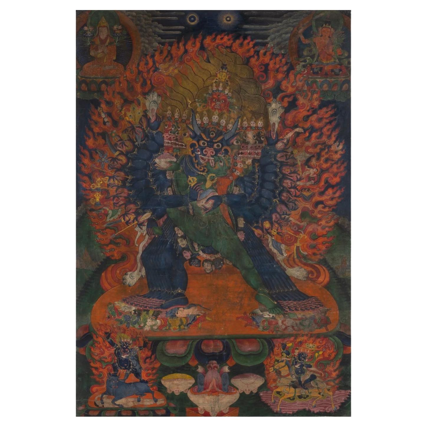 A Tibetan Yamantaka Thangka 17th/18th Century

The thangka is coloured and gilt with the fierce deity depicted striding in alidhasana surrounded by a fiery aureole. Numerous other deities and lamas are depicted surrounding the central figure. Detail