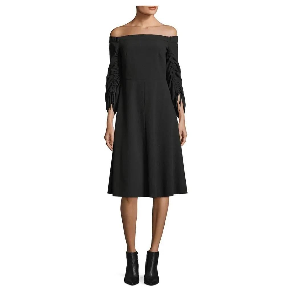 Chic et gothique, la robe noire à épaules dénudées de Tibi. Non portés. Réalisée en crêpe extensible de polyester/élasthanne noir, elle présente une coupe décolletée avec des manches 3/4 froncées, un corsage façonné, une taille rehaussée et une jupe