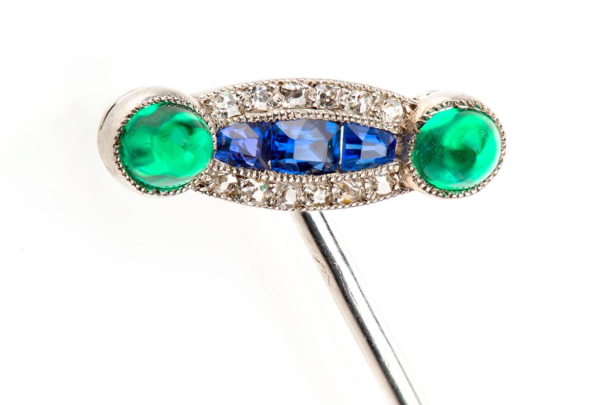 A finely made antique tie pin mounted in platinum and set with very fine coloured stones. These comprise a three stone Ceylon sapphire with a brilliant cut diamond surround with a cabochon shaped Colombian emerald either side. French marked with the