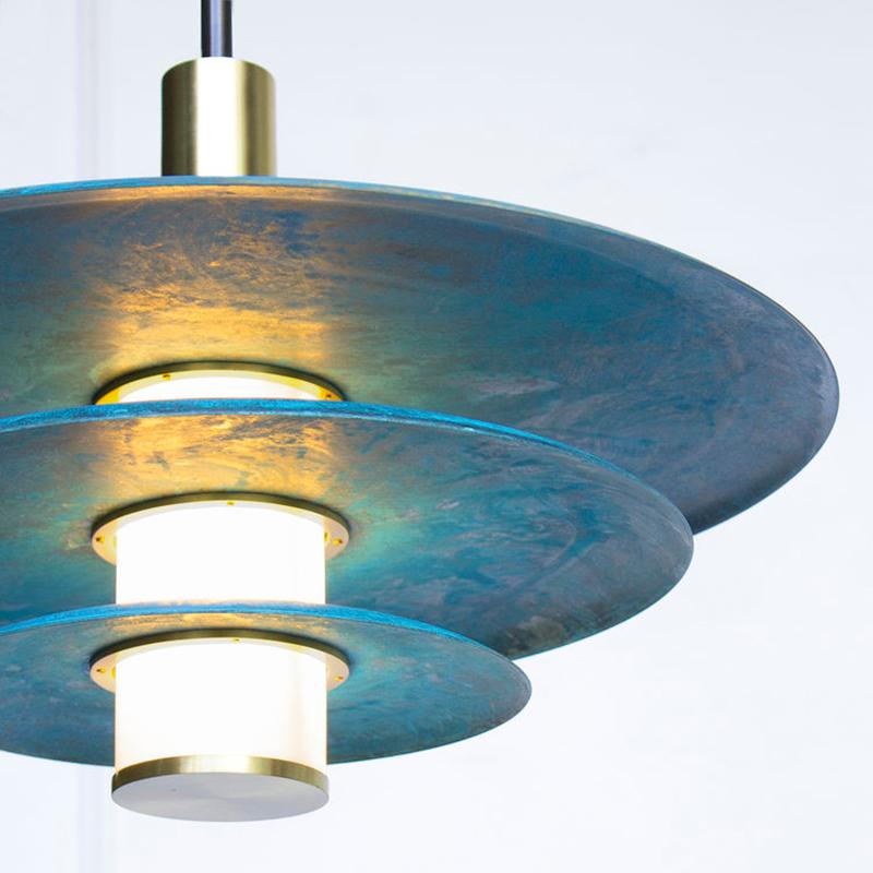 The tiered Arthur pendant embraces Trella’s Prussian blue patina in grand fashion. An internally lit white glass cylinder illuminates the depth of the hand applied patina while simultaneously providing a soft accent light. The three tiered Arthur