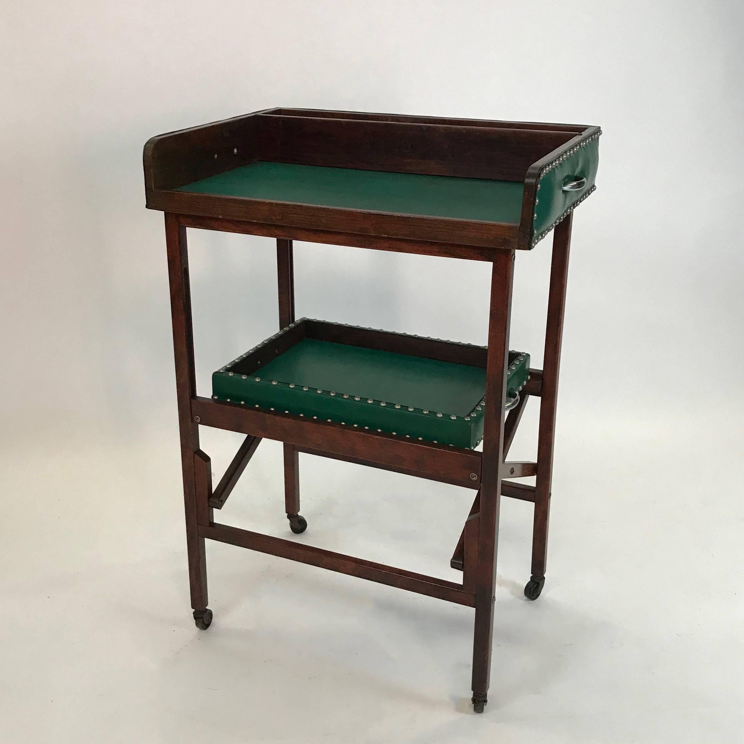Handsome, midcentury, lodge decor, two-tiered, folding bar cart features a cherry wood frame and two green vinyl trays with decorative chrome handles and nailhead details. The bottom tray measures 20 inches x 14 inches.