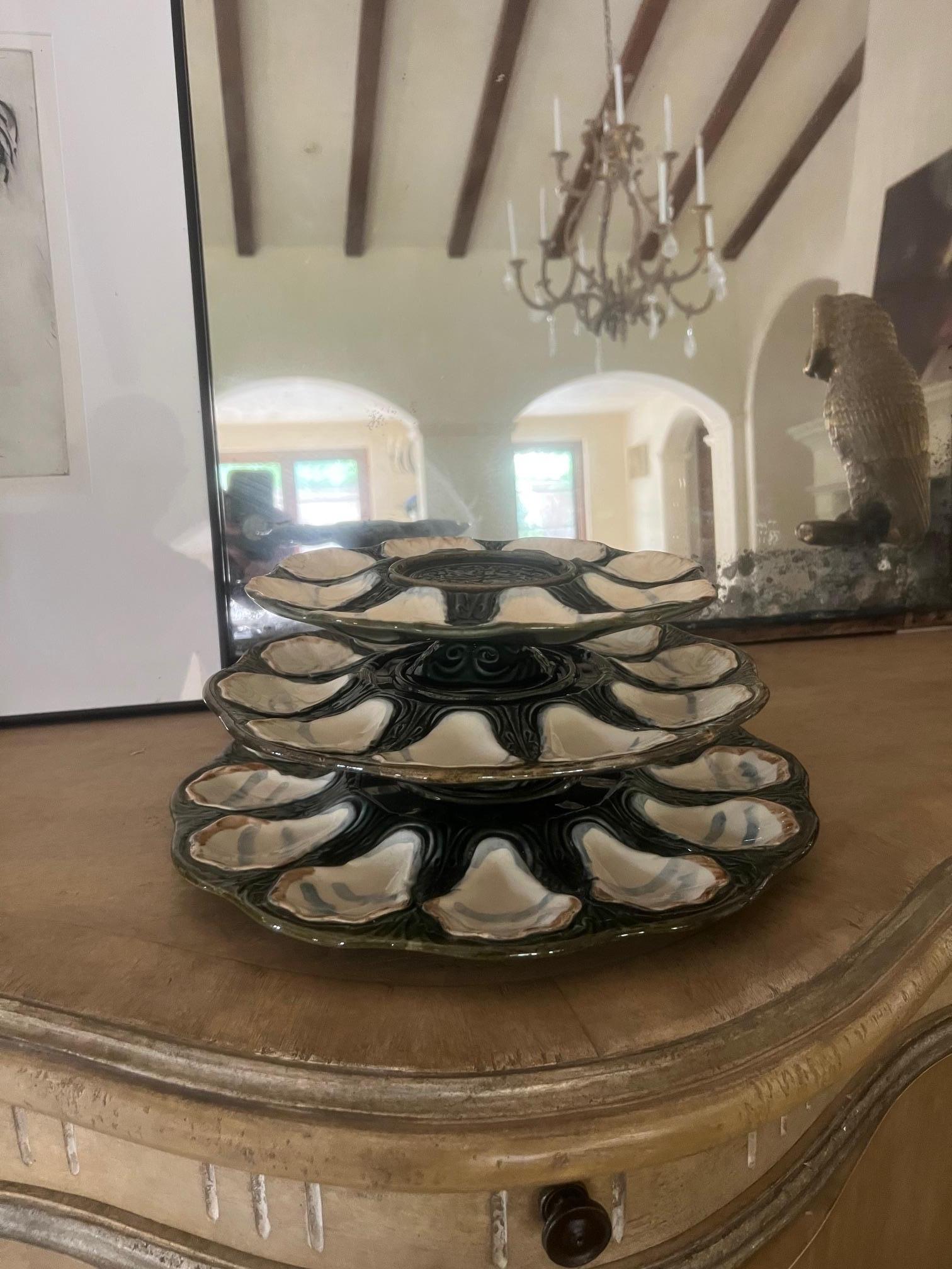 Set of three tiered oyster plates, made by Longchamp in France around 1900.  The set includes three plates that can be stacked or displayed separately, each plate has wells for oysters plus a center well for lemons or a bowl of sauce.  The total