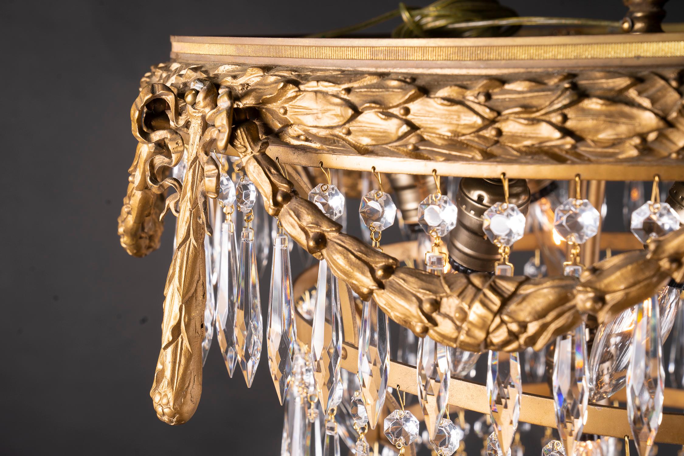 Beautiful French 19th century Louis XVI chandelier with bronze top ring and adorned with finely cast garlands and ribbons, draped with tear-dropped prisms, and nine interior lights. Circa 1890

Each piece in our shop is professionally rewired and in