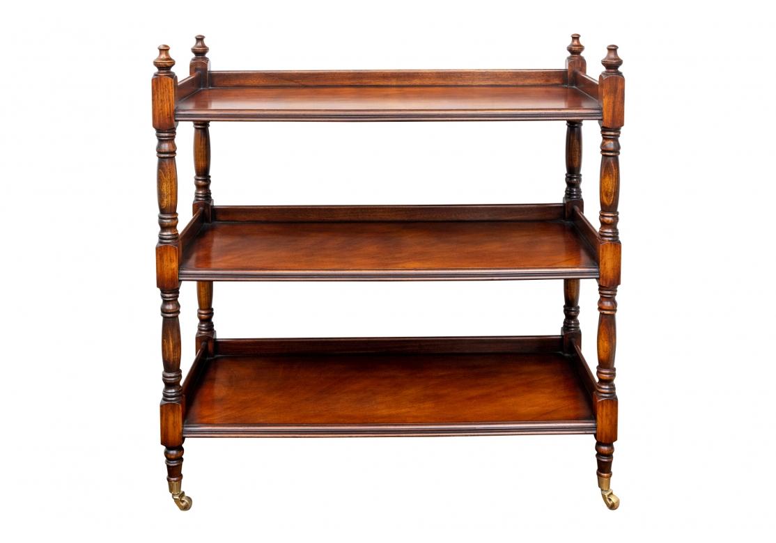 A handsome Mahogany stain open Etagere with three tiers, the top with a 3/4 gallery. Turned supports and finials, and the tiers with carved ribbed edges. Raised on brass casters.
W. 40