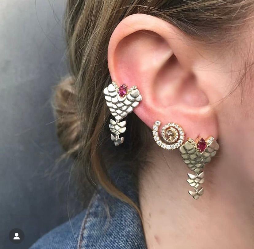 These beautiful silver earrings are embellished with solid 18k gold, within which rows of white pavé diamonds have been set to frame and draw attention to the luscious hot pink center tourmaline.
Inspired by amphibian scales, these earrings are edgy