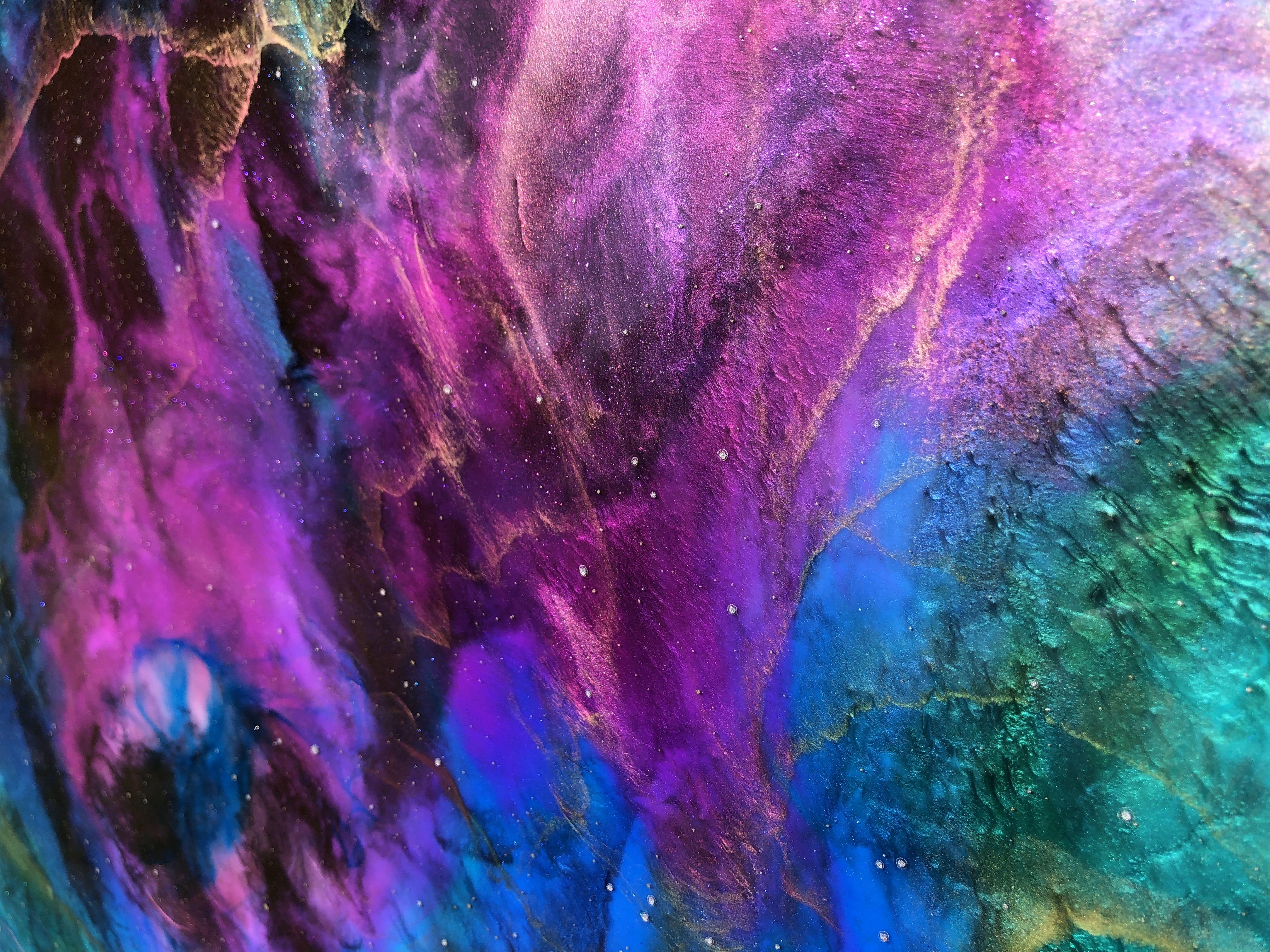 Tiffani employed her holographic resin painting technique to create the NALLORYA NEBULA, bursting with brilliant blue and purple hues, surrounded by swirling tendrils of electrifying metallic gold that seem to appear and disappear in the clouds.