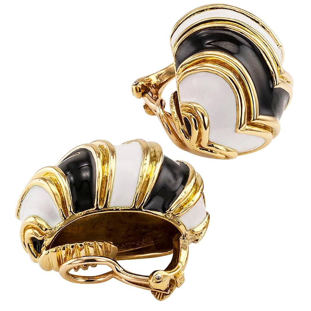 Tiffany & Co black and white enamel gold ear clips. The half hoop designs are decorated by a fanciful arrangement of fluted gold chevron patterns alternating in between black and white enamel, mounted in 18-karat yellow gold.  Make someone in your