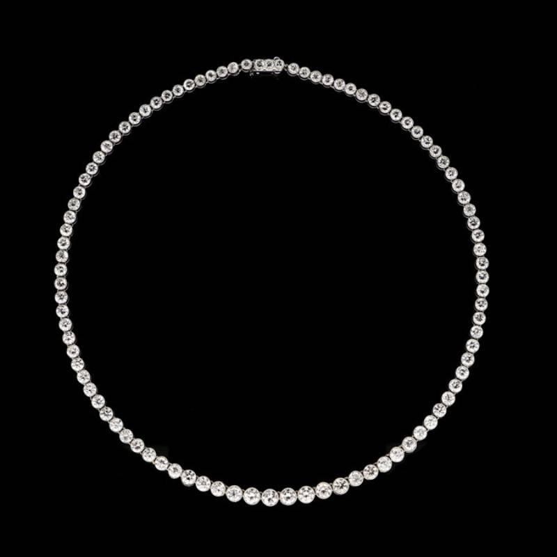 A beautifully classic diamond line necklace by Tiffany & Co. c.1930s, designed as a graduated row of round transition cut diamonds all rubover set in a highly flexible platinum mount with fine millegrain edging to a concealed tongue and box