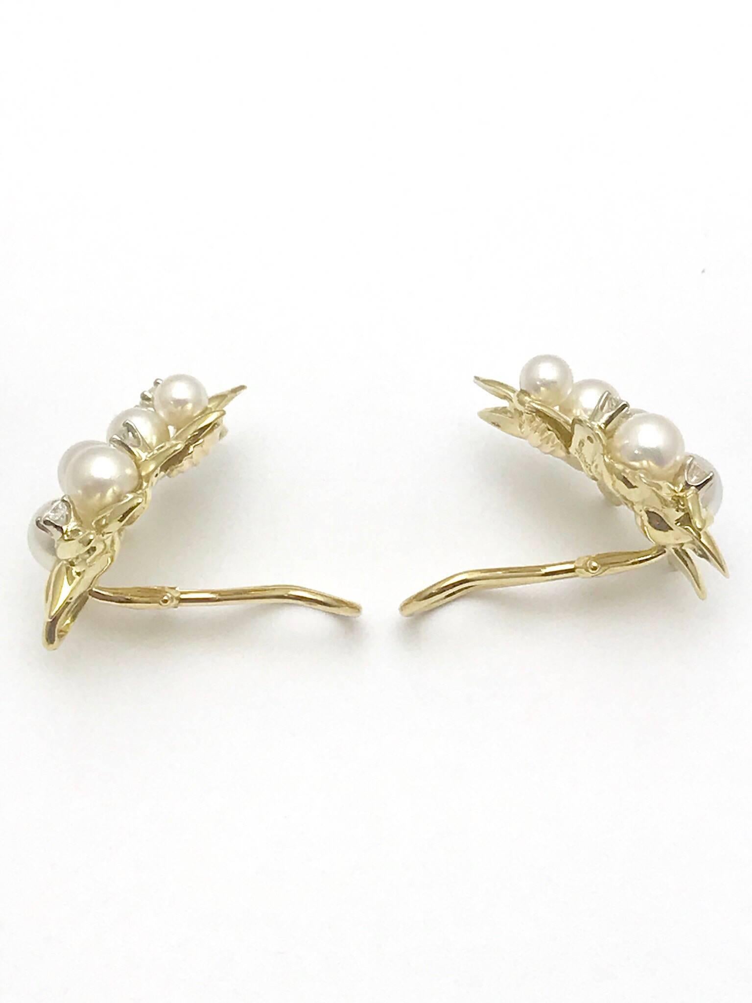 A pair of Tiffany & Co. pearl and diamond 18 karat yellow gold leaf clip earrings.  There are five pearls on each earring of varying sizes, with four round brilliant diamonds on each as well.  The eight diamonds have a total carat weight of 0.54,