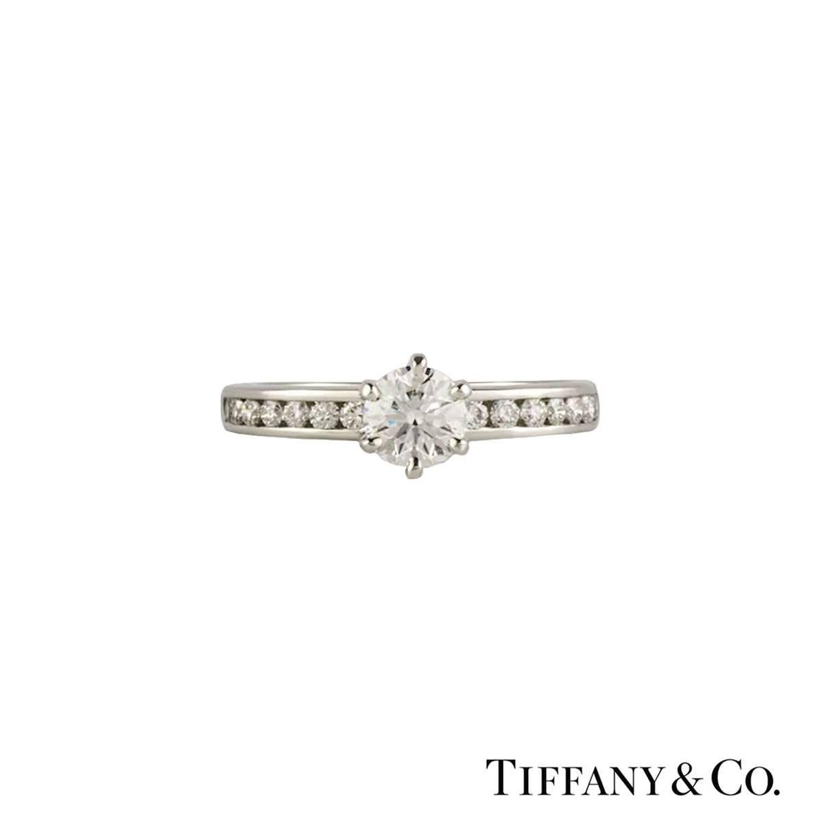 A beautiful Tiffany & Co. diamond engagement ring from The Tiffany Setting with Diamond Band collection. The ring comprises of a round brilliant cut diamonds in a prong setting with a weight of 0.33ct, G colour and VS1 clarity. The ring features 7