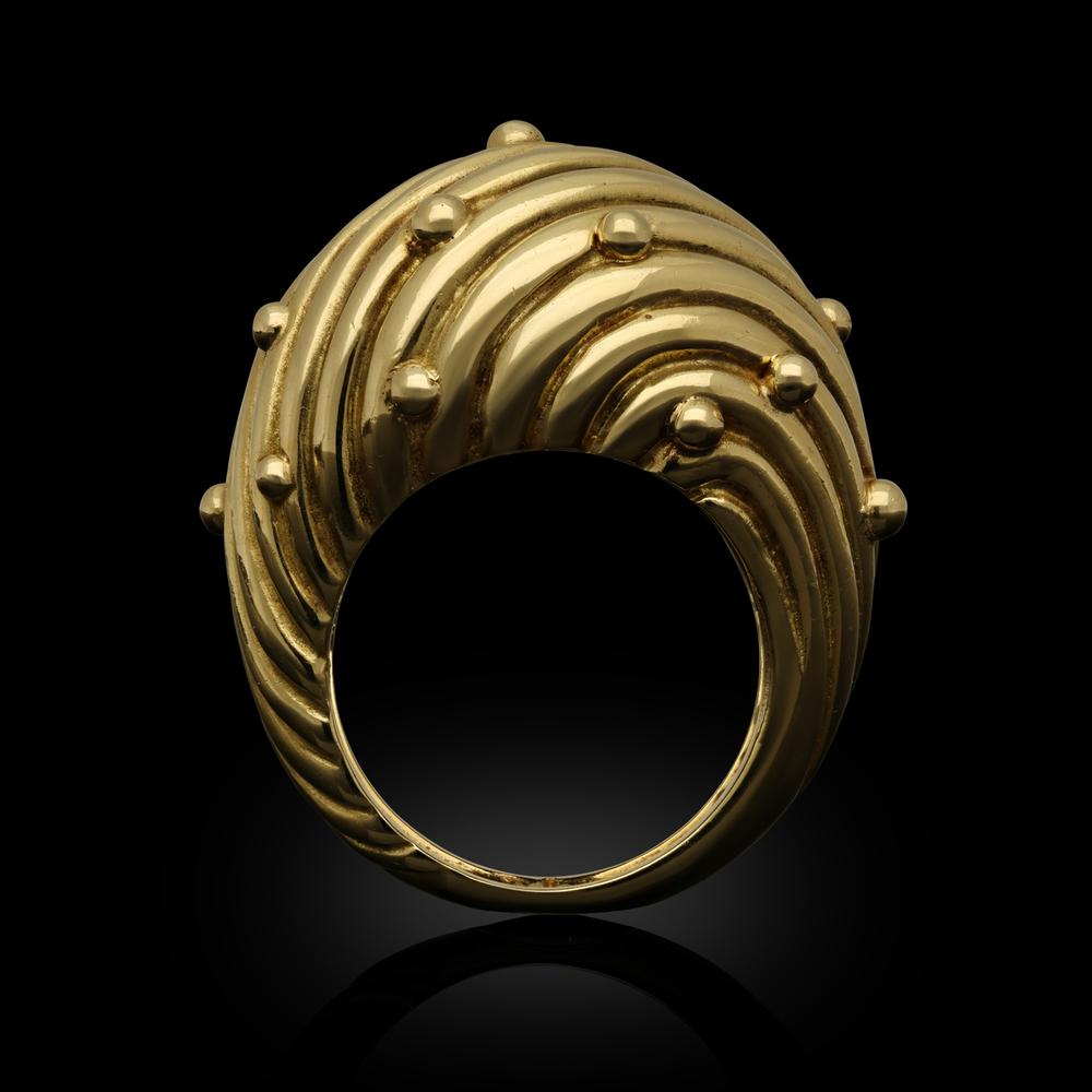 A stylish vintage 18ct gold dress ring by Tiffany & Co. circa 1970s, the ring of bold bombe design featuring a swirled effect across the whole ring, the high dome further decorated with a scattering of spherical gold beads, to tapering shoulders and