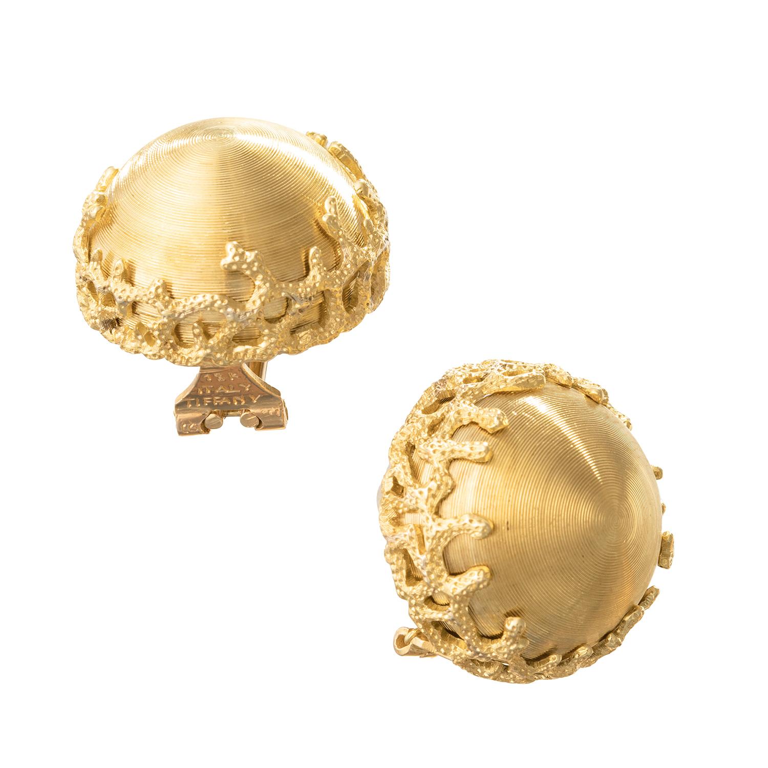 Clip earrings in 18k yellow gold, featuring a graduating concentric circle-lined conical dome center with textured coral branch motif rim.  Hinged omega-style clip backs (posts may be added upon customer request).  Signed 