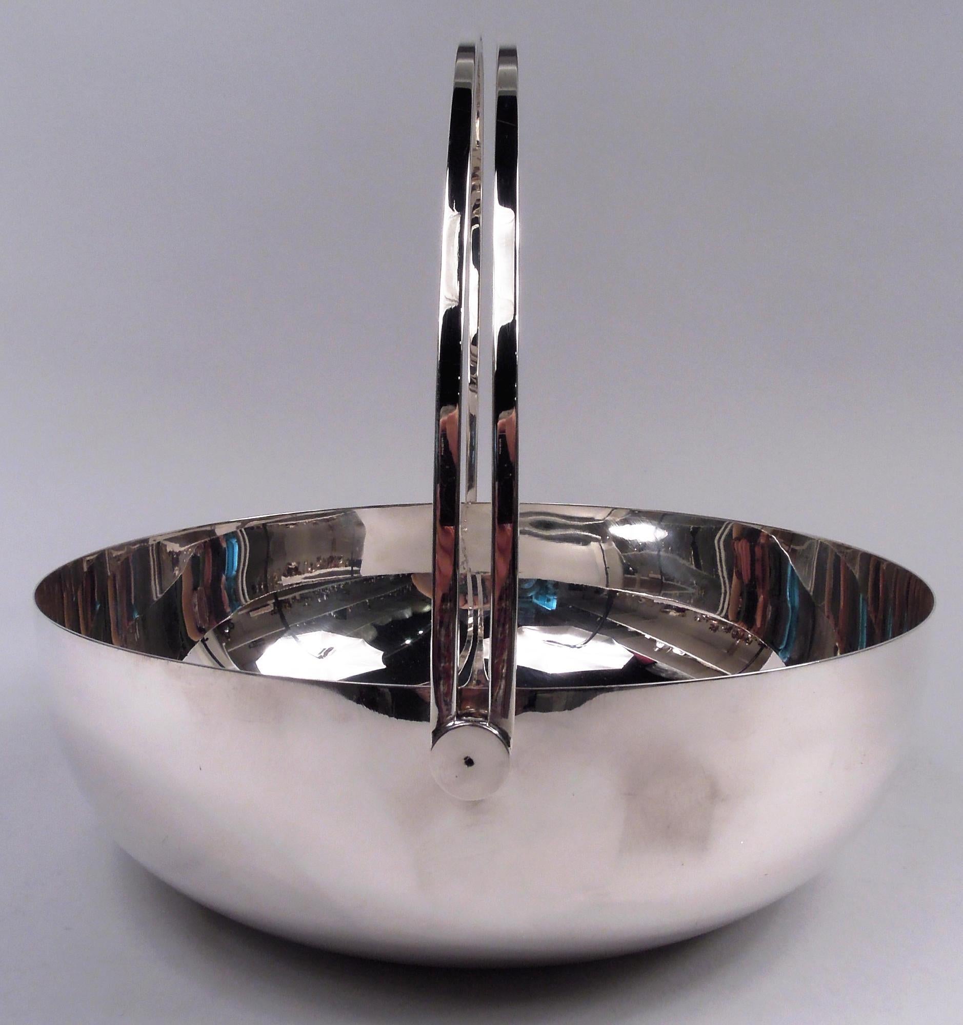 Eighties big and bold sterling silver basket. Round and curved bowl with swing-mounted open c-scroll handle. Capacious. A great piece from the Want-It-All years. Marked “Tiffany & Co. Sterling / Italy”. Heavy weight: 57 troy ounces.