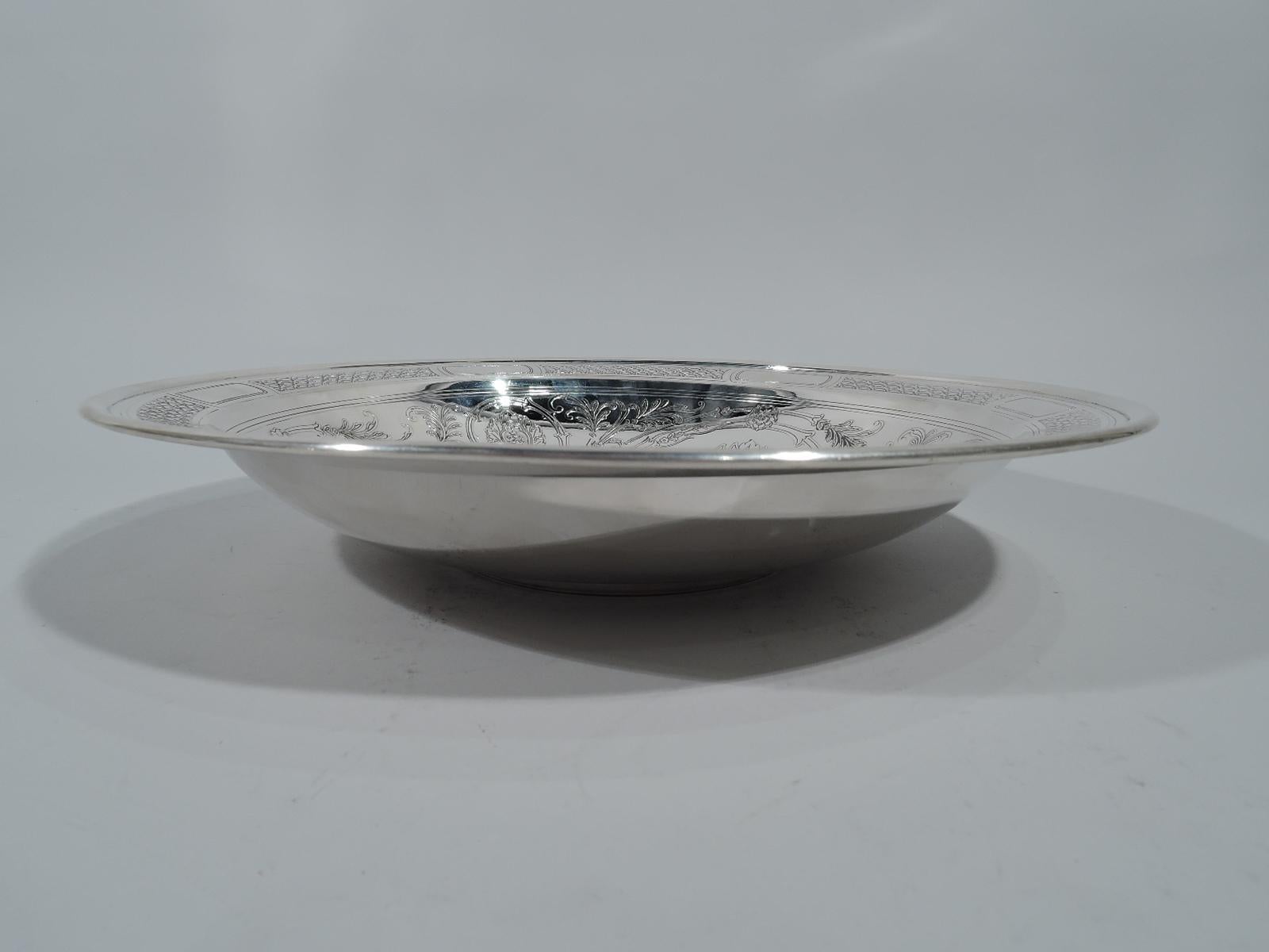 Aesthetic sterling silver bowl. Made by Tiffany & Co. in New York, circa 1914. Round with molded rim and foot ring. Acid-etched interior: A bird with patterned plumage and loose foliate scrolls with flame flowers. Rim has cartouches (vacant)