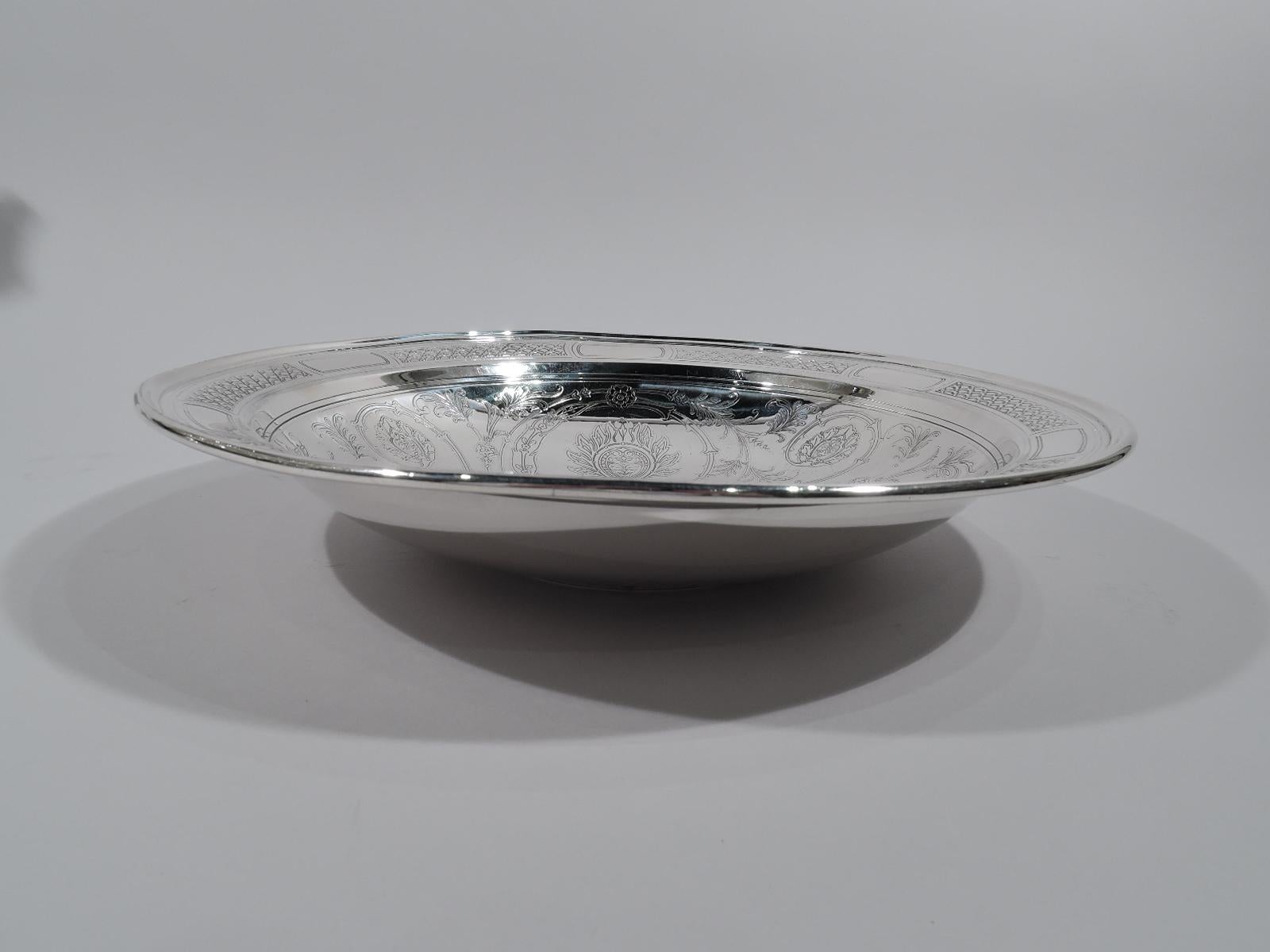 Aesthetic sterling silver bowl. Made by Tiffany & Co. in New York, ca 1914. Round with molded rim and foot ring. Acid-etched ornament. In well a bird with patterned plumage and loose foliate scrolls with flame flowers. Rim has tubular frames