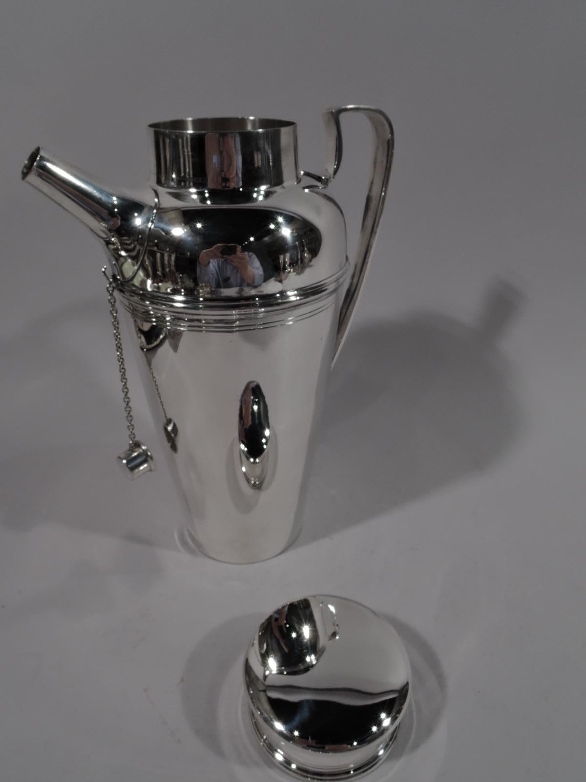 Art Deco sterling silver cocktail shaker. Made by Tiffany & Co. in New York, circa 1925. Straight and tapering bowl with curved shoulder, high-looping scrolled bracket handle, short neck with overhanging flat-topped cover, and stubby, tapering spout