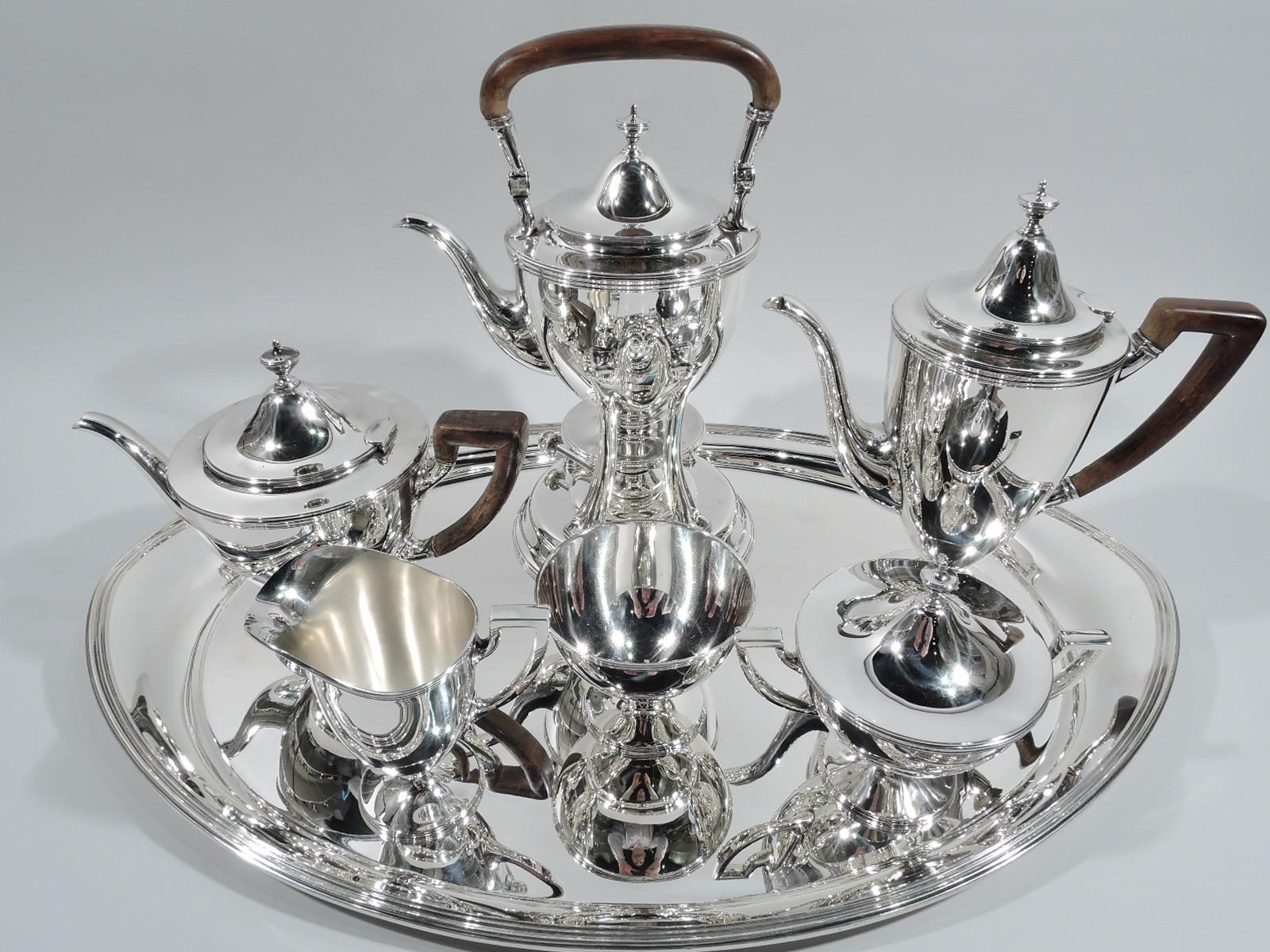 American Classical sterling silver 6-piece coffee and tea set on tray. Made by Tiffany & Co. in New York, ca 1915. This set comprises hot water kettle on stand, coffeepot, teapot, creamer, sugar, and waste bowl. Each: Curved and tapering body on