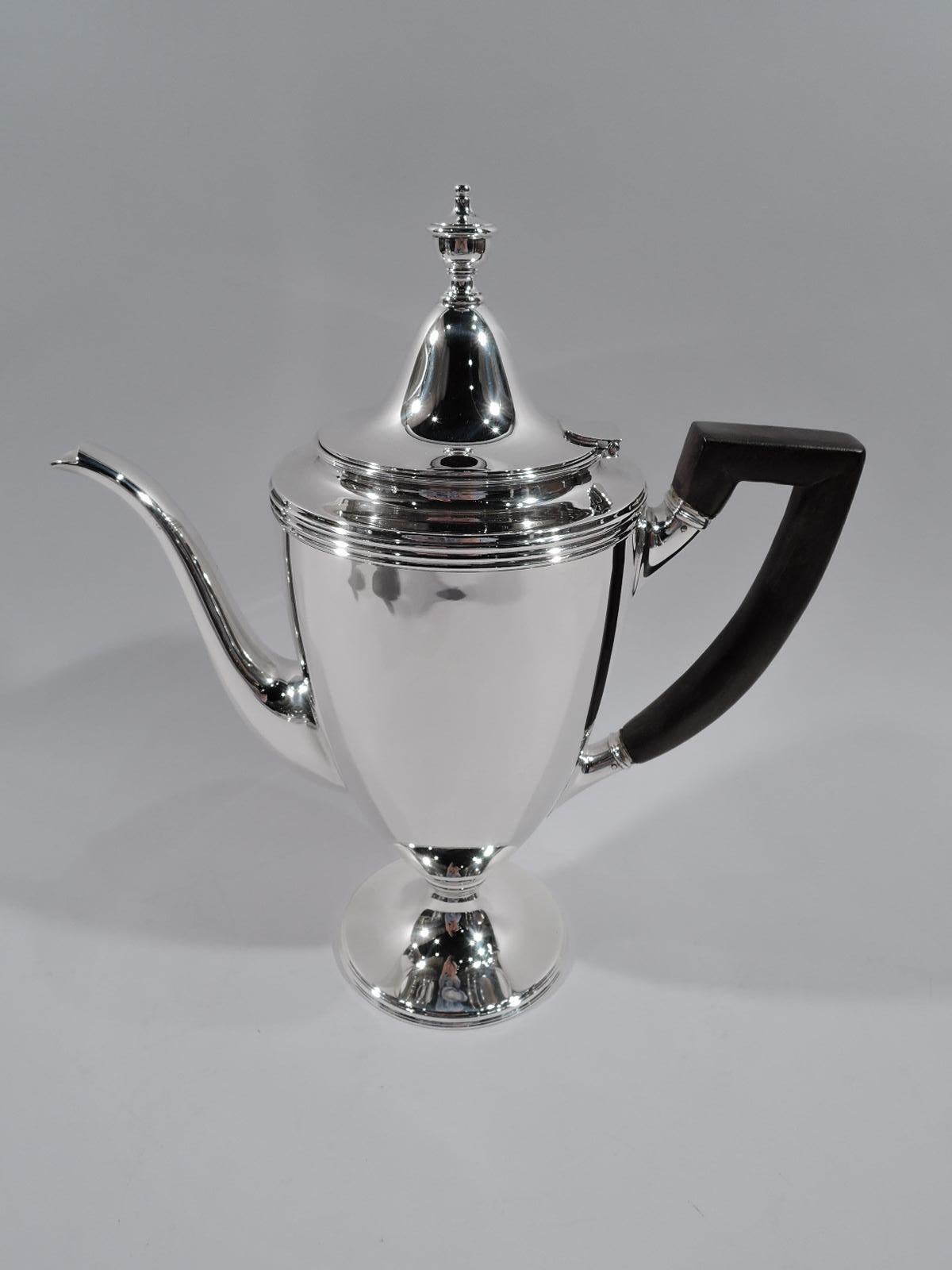 American Classical sterling silver 3-piece coffee set. Made by Tiffany & Co. in New York. Each: Curved and tapering body on stepped and raised foot. Handles scroll bracket; coffeepot handle stained wood. Covers domed with vase finial. Coffeepot has